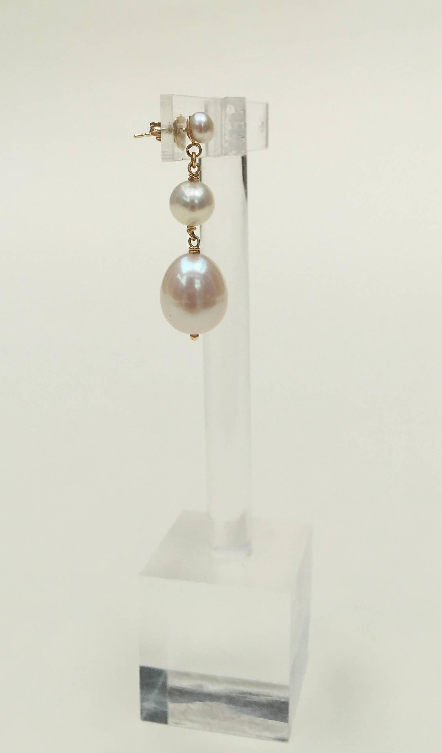 These classic earrings have two small round pearls and tear drop pearl (.4 x .6 of an inch) finishing off the earring. The glow of the white pearls are highlighted with the shine of the 14k yellow gold wiring and stud. At 1.5 inches these pearls are