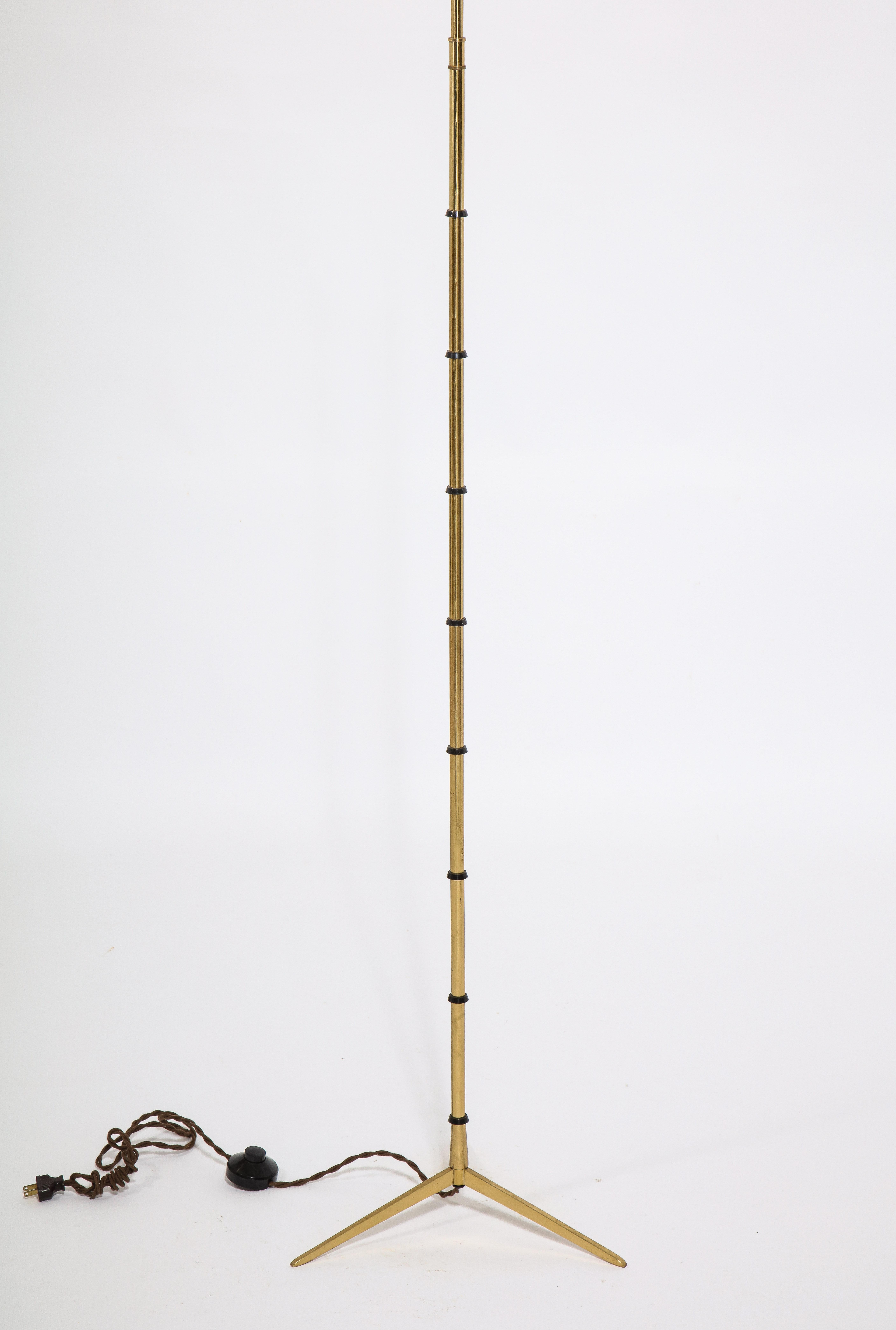 A tripod brass floor lamp in the manner of Jansen, the stem is a stylized faux bamboo with rings of different patinas. Shade is for photographic purposes.