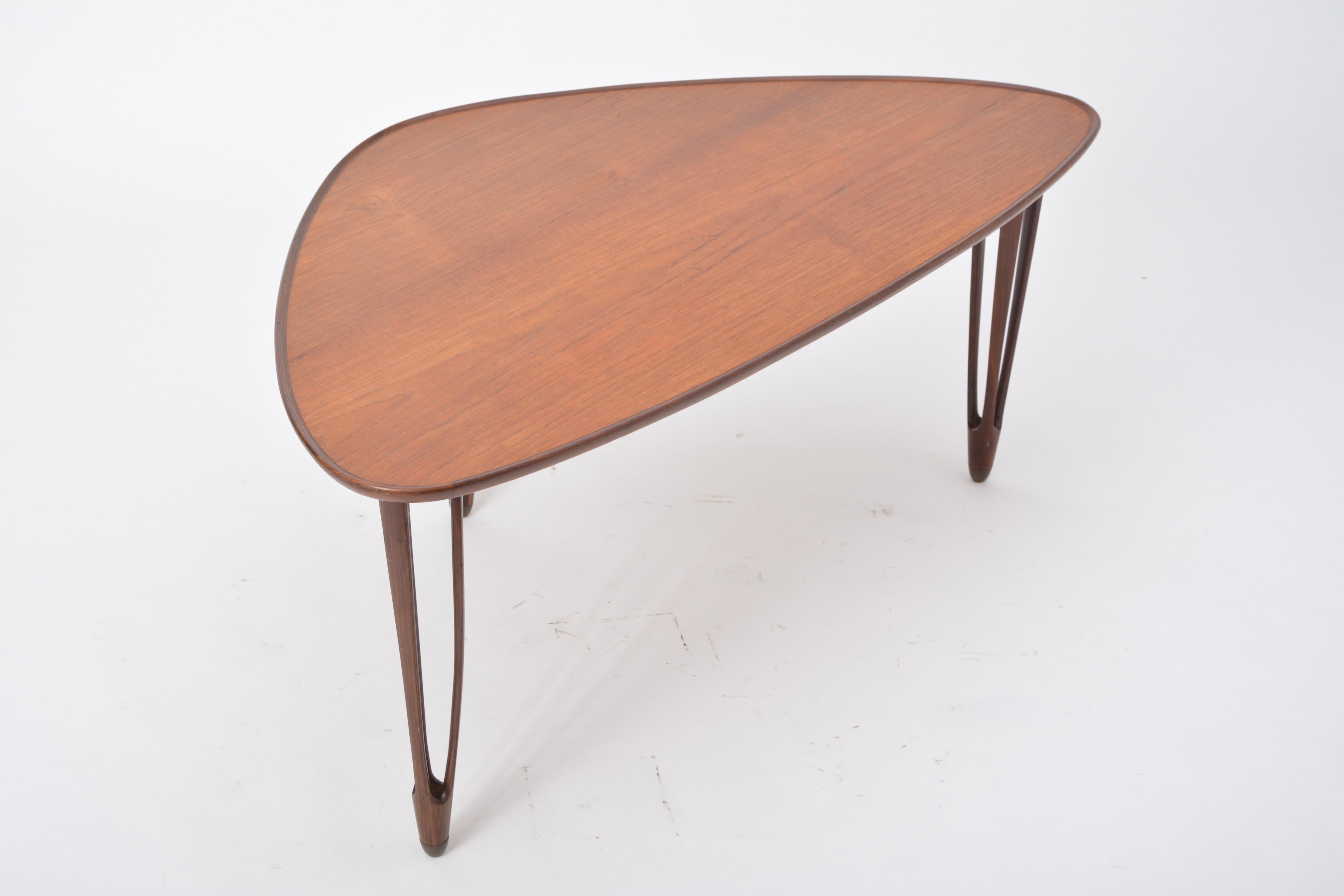 Asymmetrical tripod coffee table made from teak wood. Rounded edges, brass feet, produced by Danish company B.C. Møbler in the 1950s.