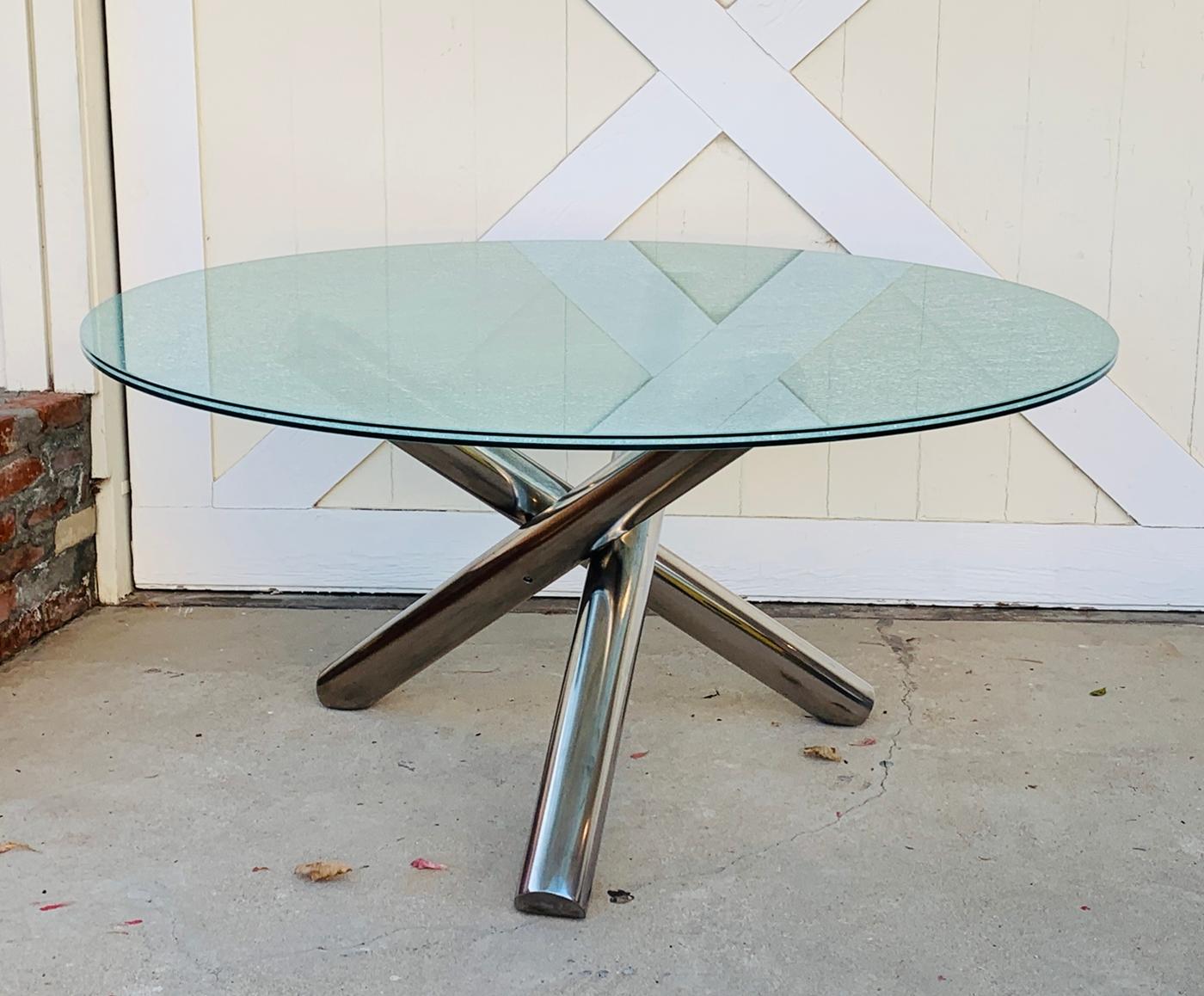 Three intertwined stainless steel posts are fused together, forming the beautiful look of the this tripod Dining Table. A truly futuristic modern looking design. The table comes with a 48 inch crackled glass top creating the finished look that's