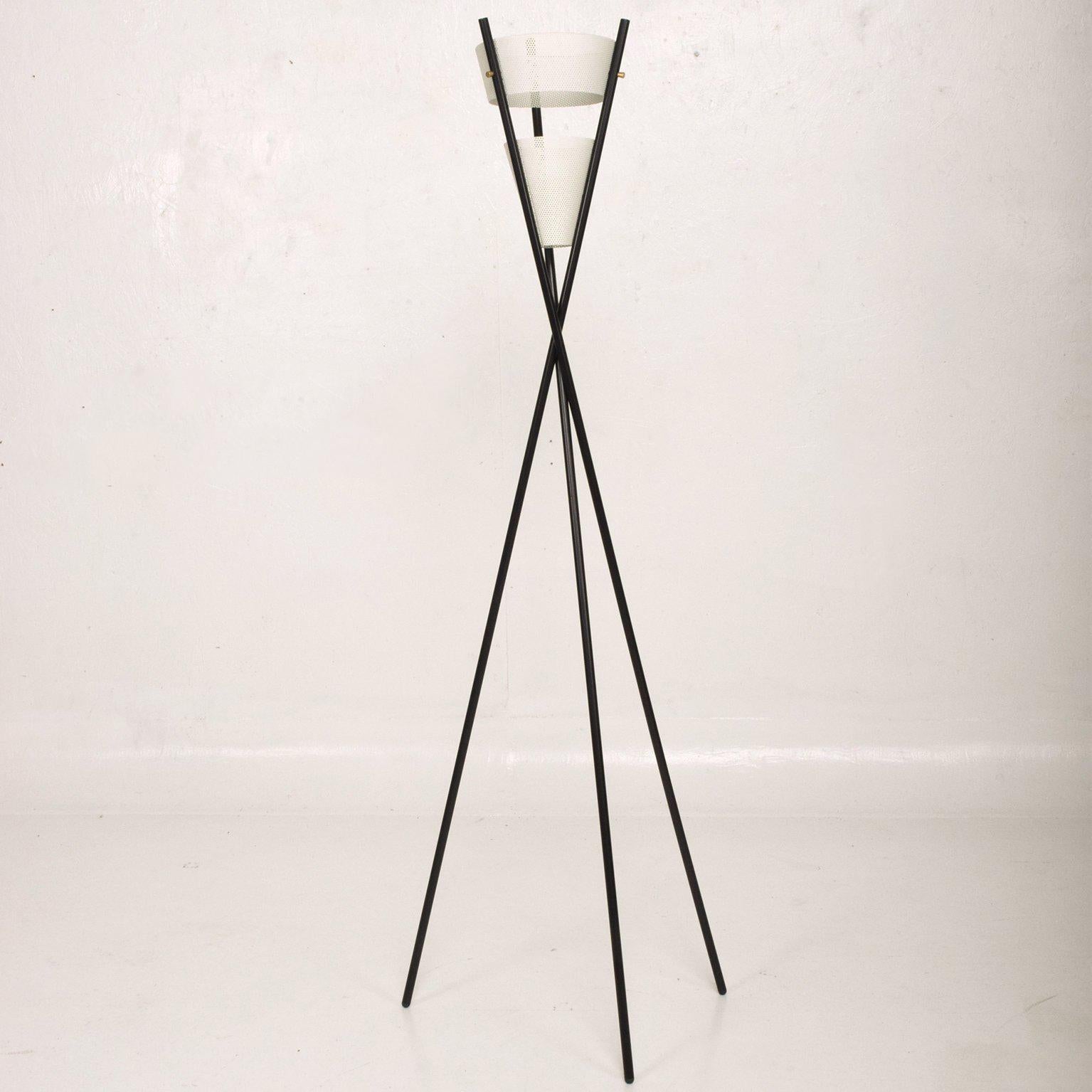 We are pleased to offer for you a floor lamp with tripod base in black finish with perforated metal shades painted in white.  Price $1,500 per floor lamp. Only one available left.

No information on the maker. 

Measures: 53" tall x 18" in