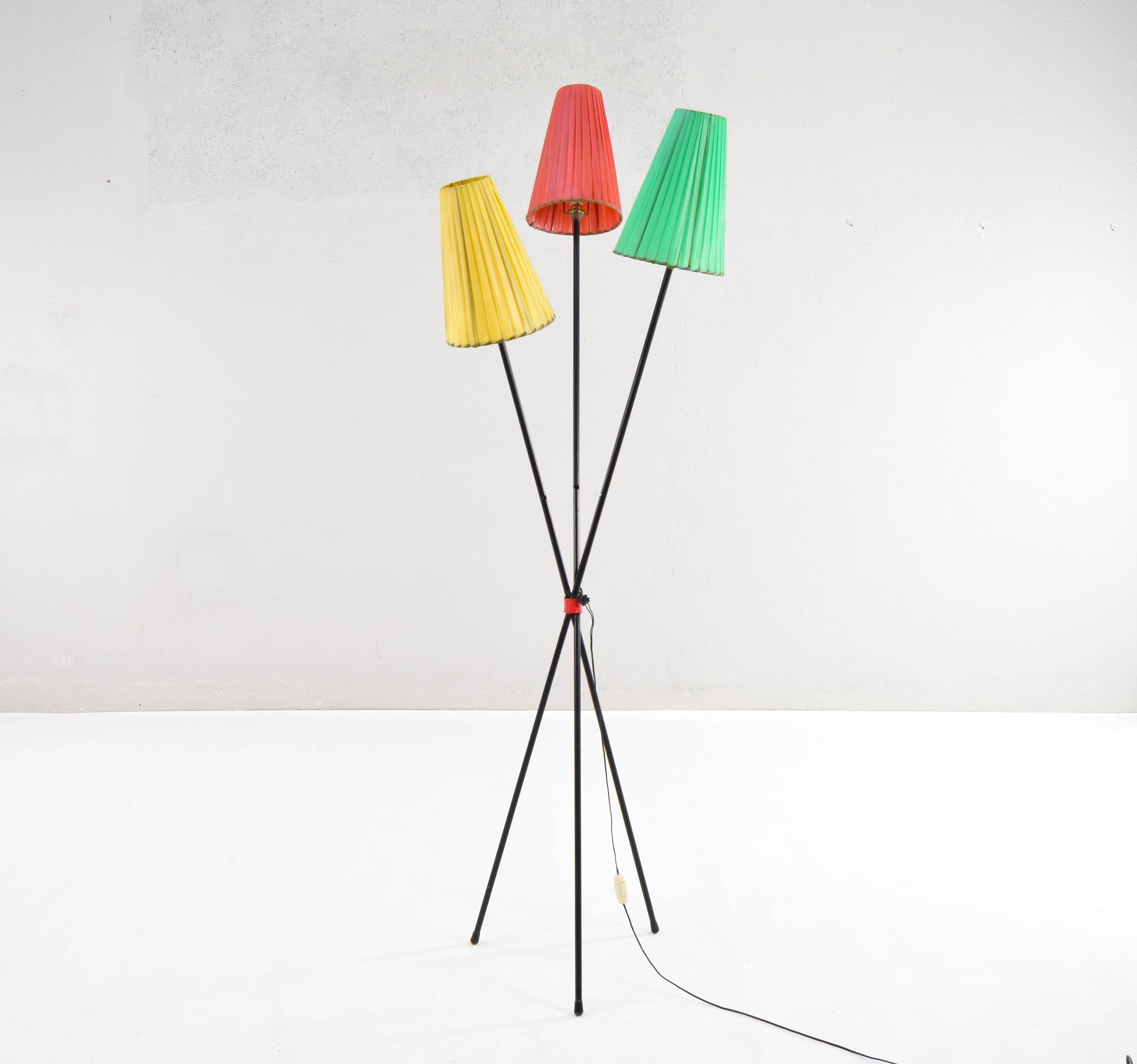 Tripod French floor lamp attributed to the master Matheu Matégot. 
Composed of three iron bars that intersect at a point held by steel covered in red. 
Each of the bars ends in a luminaire with its respective colorful conical screen with plastic