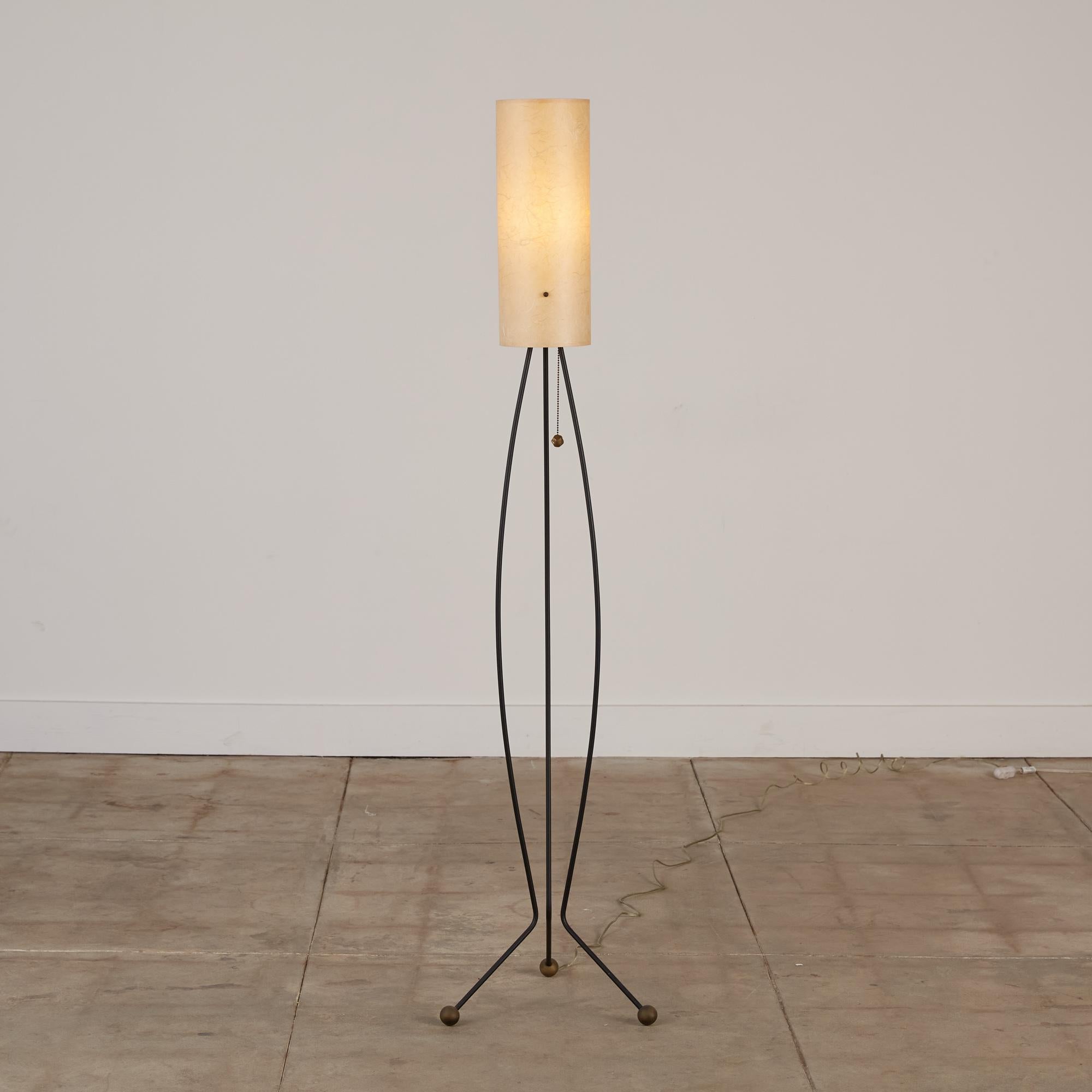 This tripod floor lamp features a patina most people wait decades to achieve. Each delicate leg curves down the length of the lamp and is finished with a brass footing. The paper pulp lamp shade gives off a warm golden toned light and is secured by