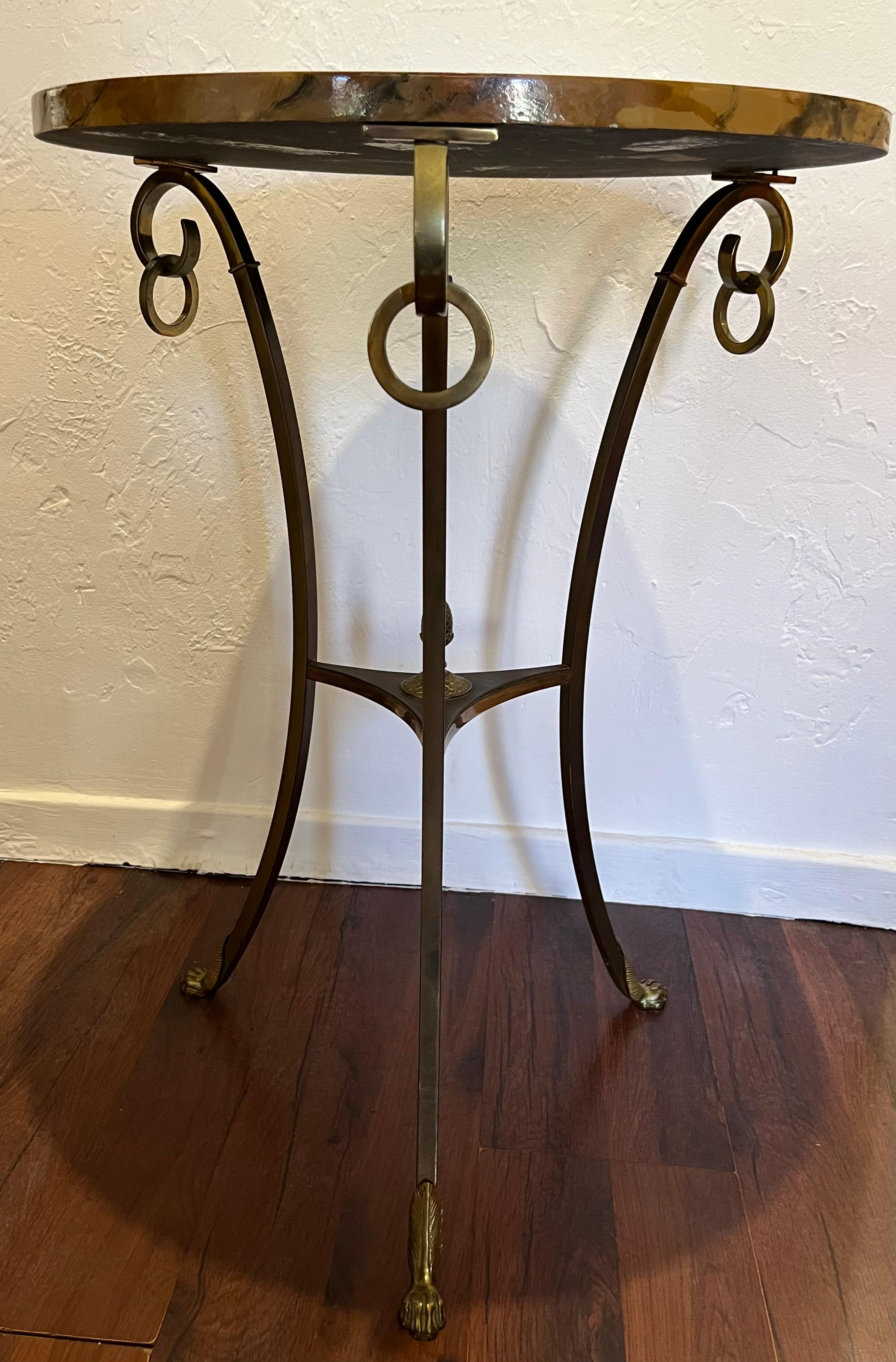 Bronze pedestal table, painted and varnished top with geometric patterns on tripod strut base decorated with a pine cone, ending in lion paws. Decorated with removable rings. Signed 