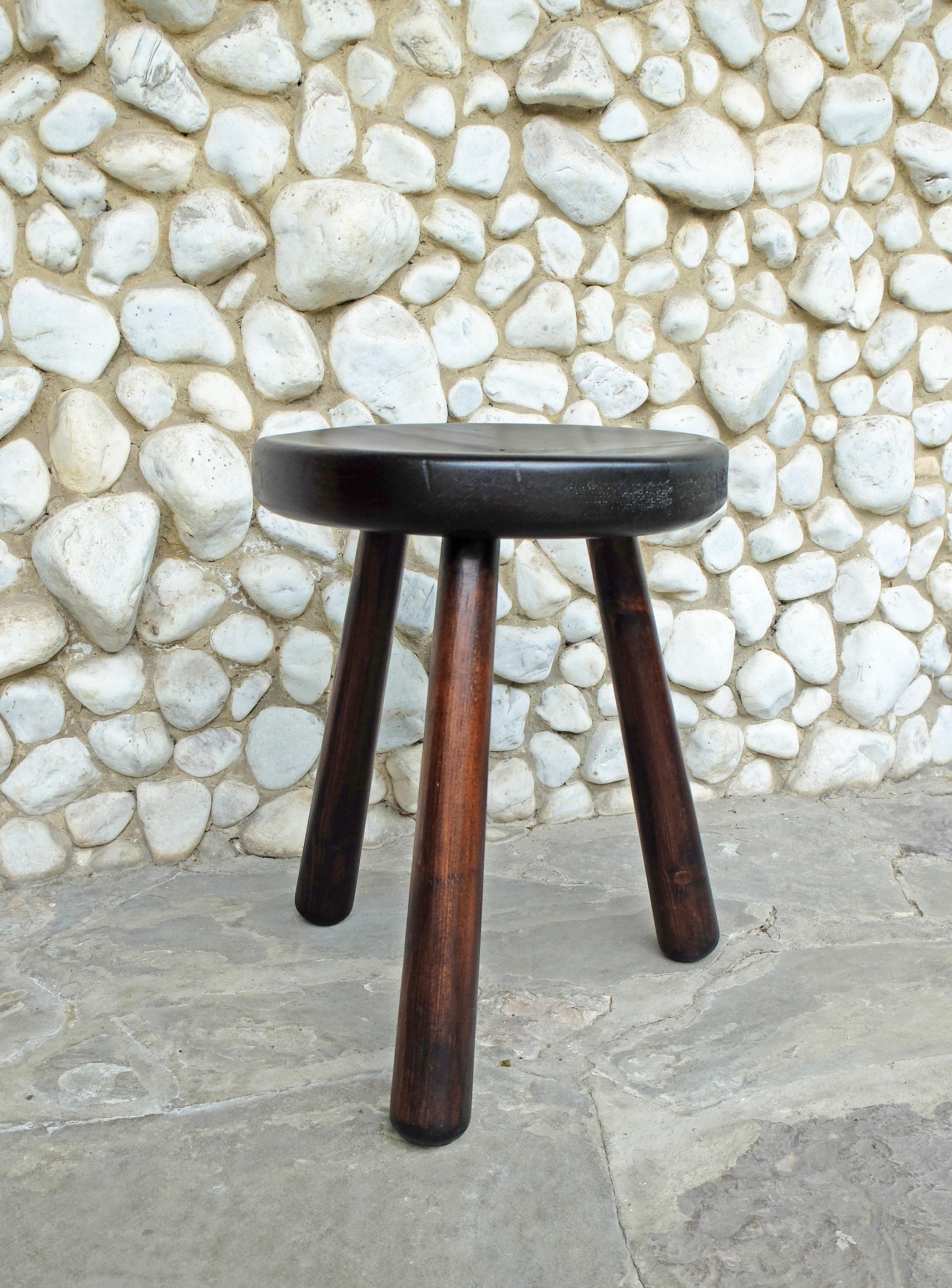 Tripod stool made of solid pinewood. Vintage, made in France in the 1960s or 1970s.

In the style of the stools Charlotte Perriand designed for the French Ski resorts of Les Arcs and Meribel. 
The traditional assembly techniques and the concave