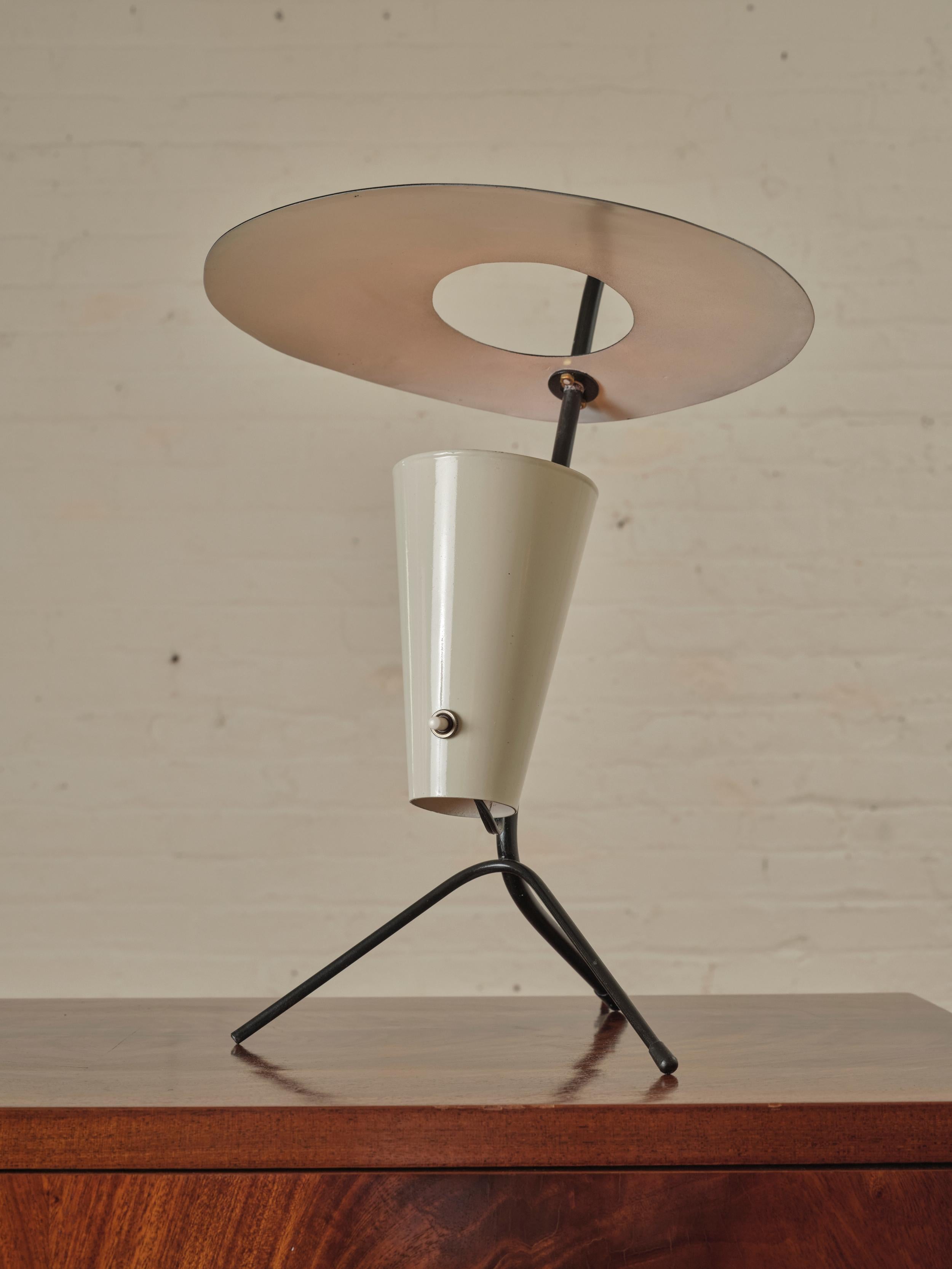 Französische Dreibein-Tischlampe, Pierre Guariche zugeschrieben. Die Leuchte wird von einem schicken emaillierten Metallscheibenschirm gekrönt, der von einem dreibeinigen Sockel getragen wird, der dem Design Stabilität und ein skulpturales Element