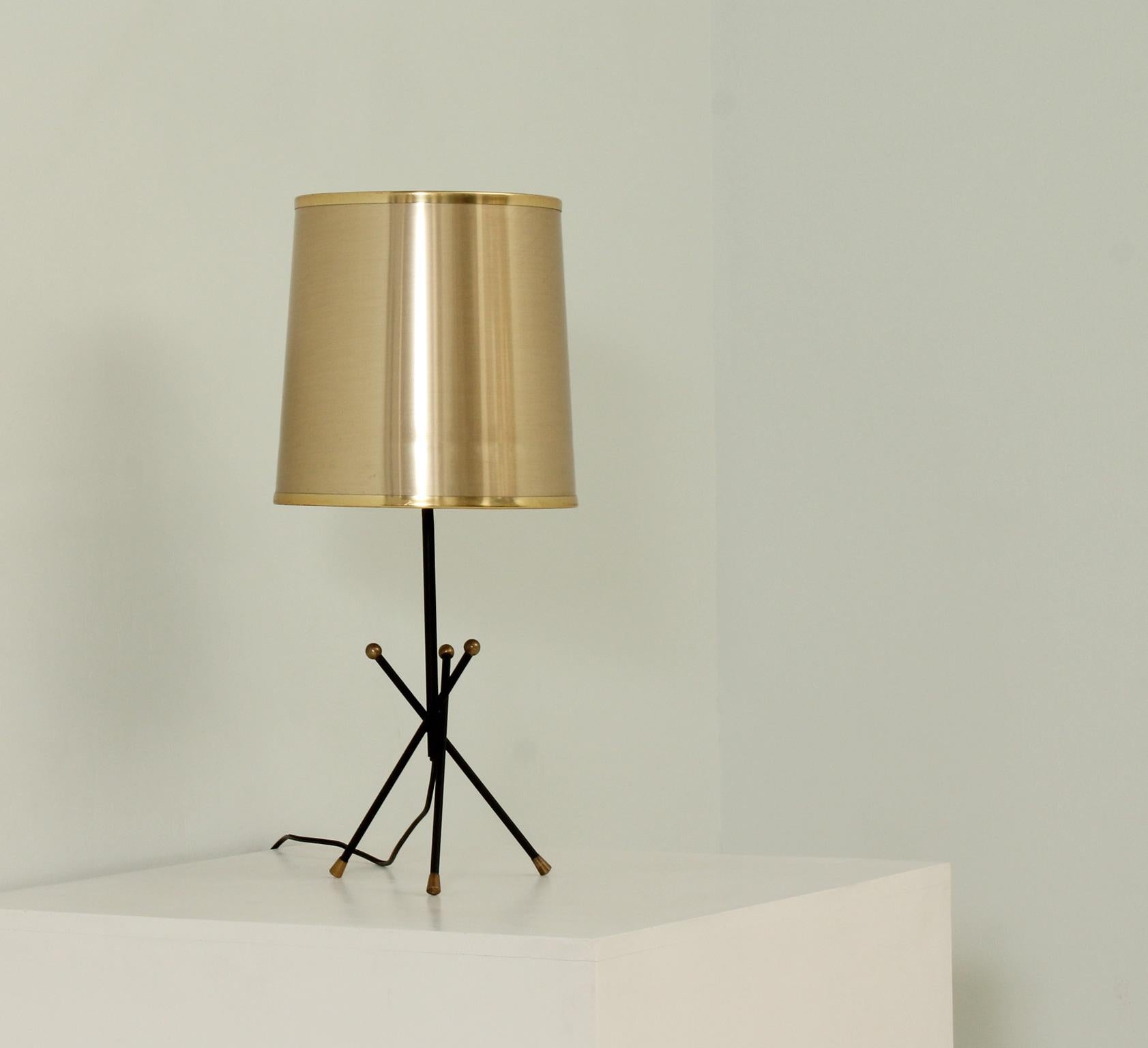 Tripod table lamp from 1950's, Spain. Black metal base with brass details, the shade is later in gold plastic.