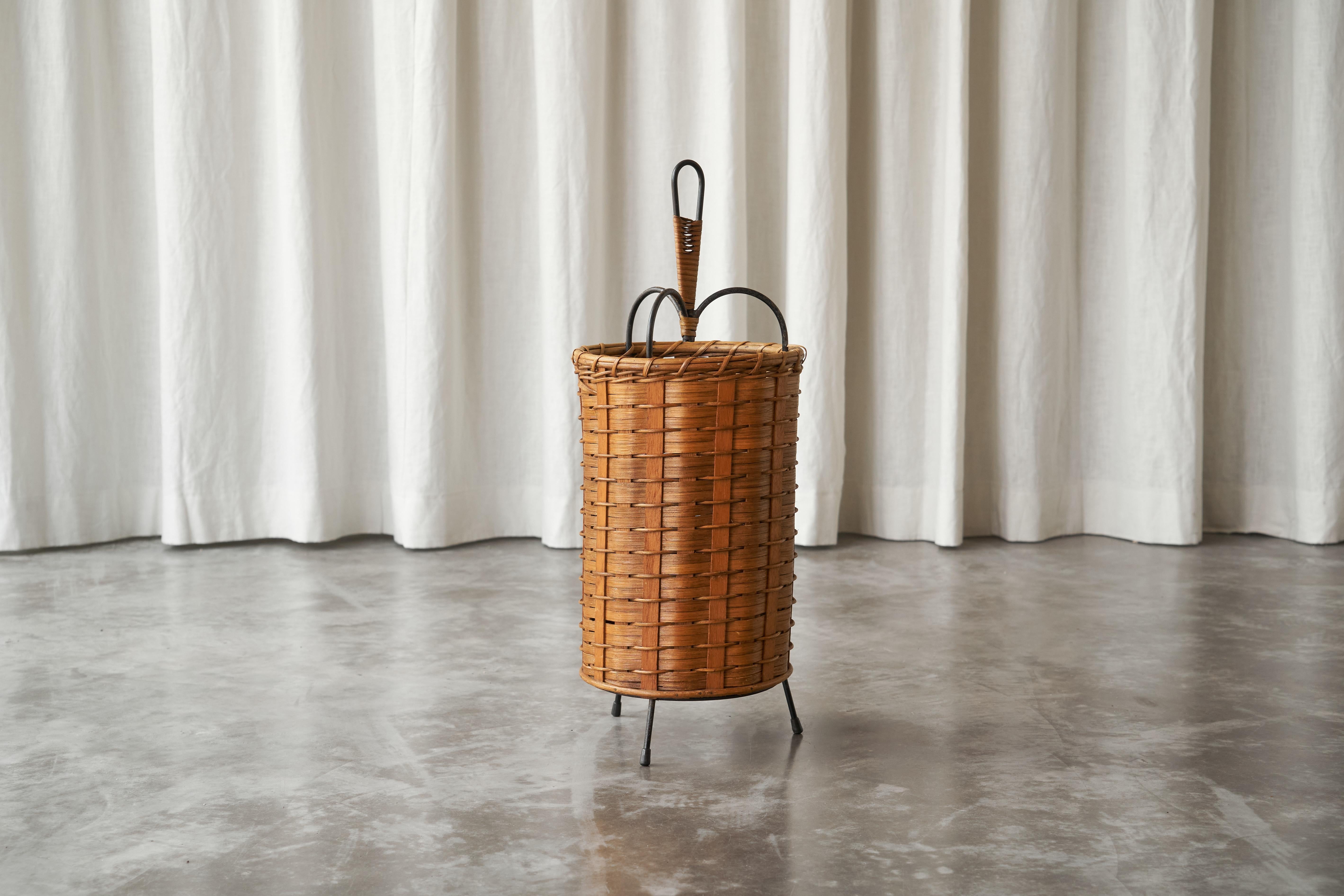 Tripod Umbrella Stand in Rattan and Metal, Europe, 1960s.

This is a wonderful and charming umbrella stand in rattan and metal, made somewhere in the 1960s.

The body of the stand is made from woven rattan, which gives it a warm, natural appearance