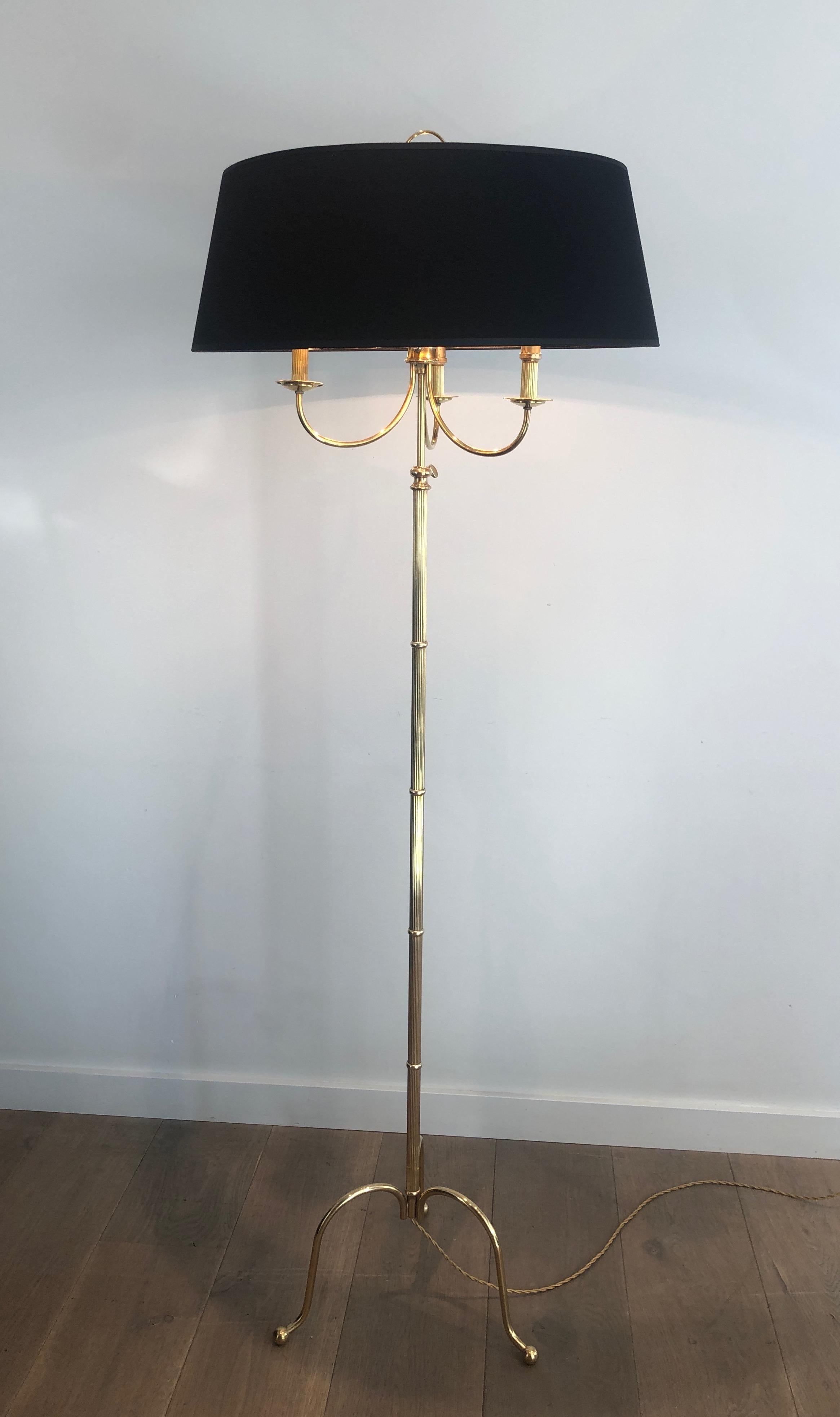This neoclassical style tripode floor lamp is made of brass. It has 3 arms and is adjustable in height. This is a French work by famous designer Maison Jansen. Circa 1940.