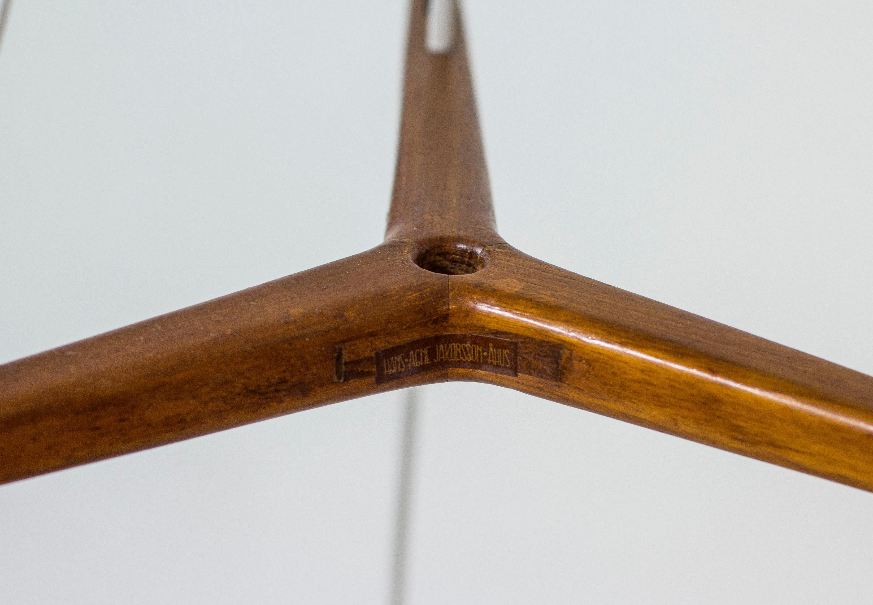 Tripple pendant lamp designed by Hans-Agne Jakobsson. Produced by his own company in Åhus during the 1950s. Three solid brass shades and ceiling mount with teak details and solid teak triangle that separate the shades. Signed with label. Good