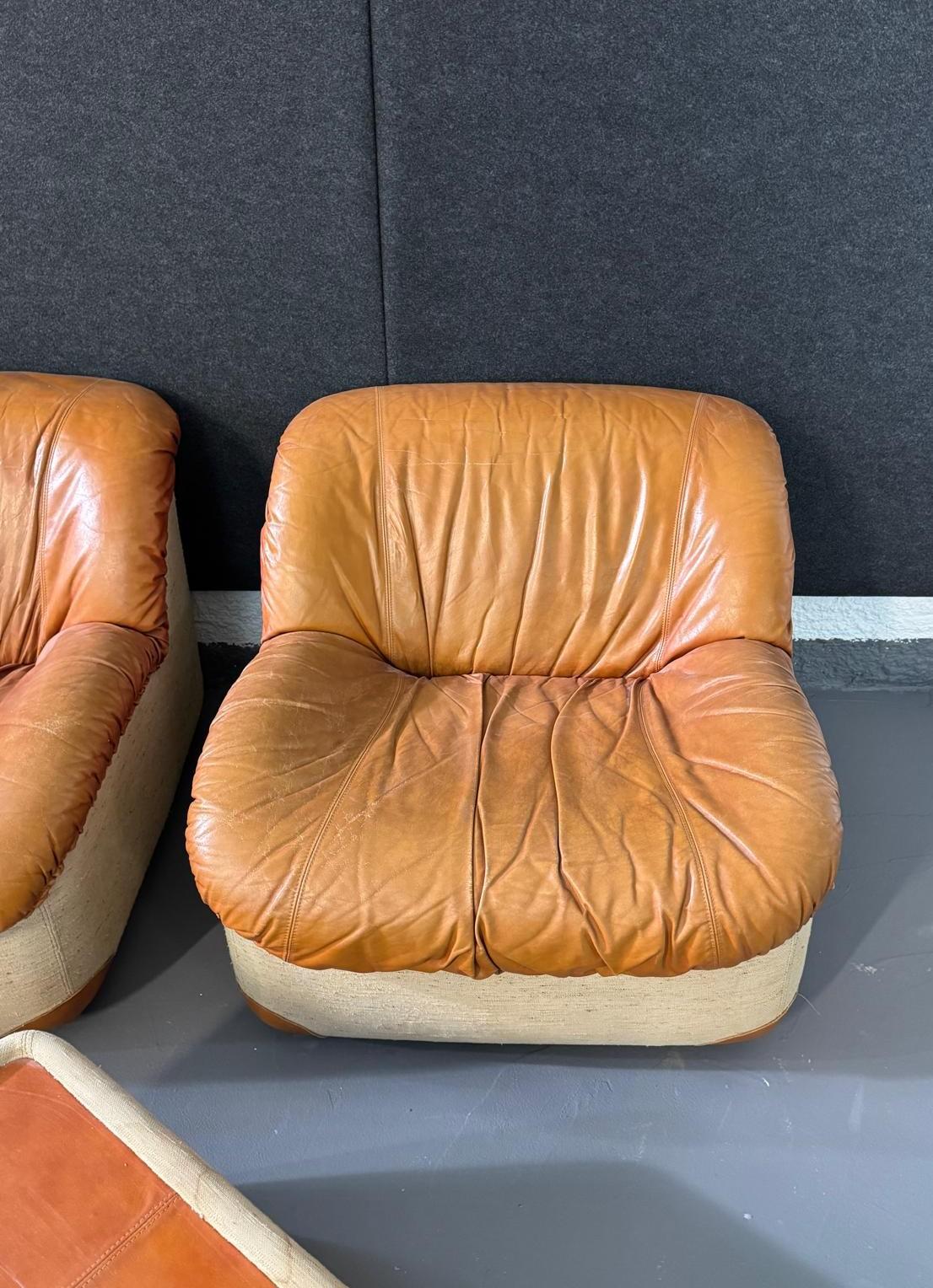 Tres sillones con dos mesas de centro/reposapiés de cuero 'Caprice' de Henning Korch para Swan. Los sillones tienen una estructura de poliuretano y tela, con asiento y respaldo de cuero. Las mesas de centro están tapizadas en tela con cuero en la