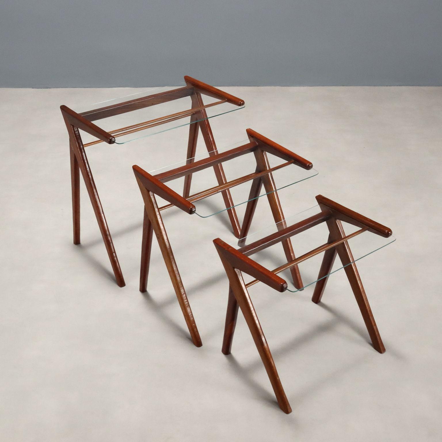 Set di tavolini a nido di manifattura italiana del XX secolo con struttura in legno impiallacciato teak e piano in vetro.