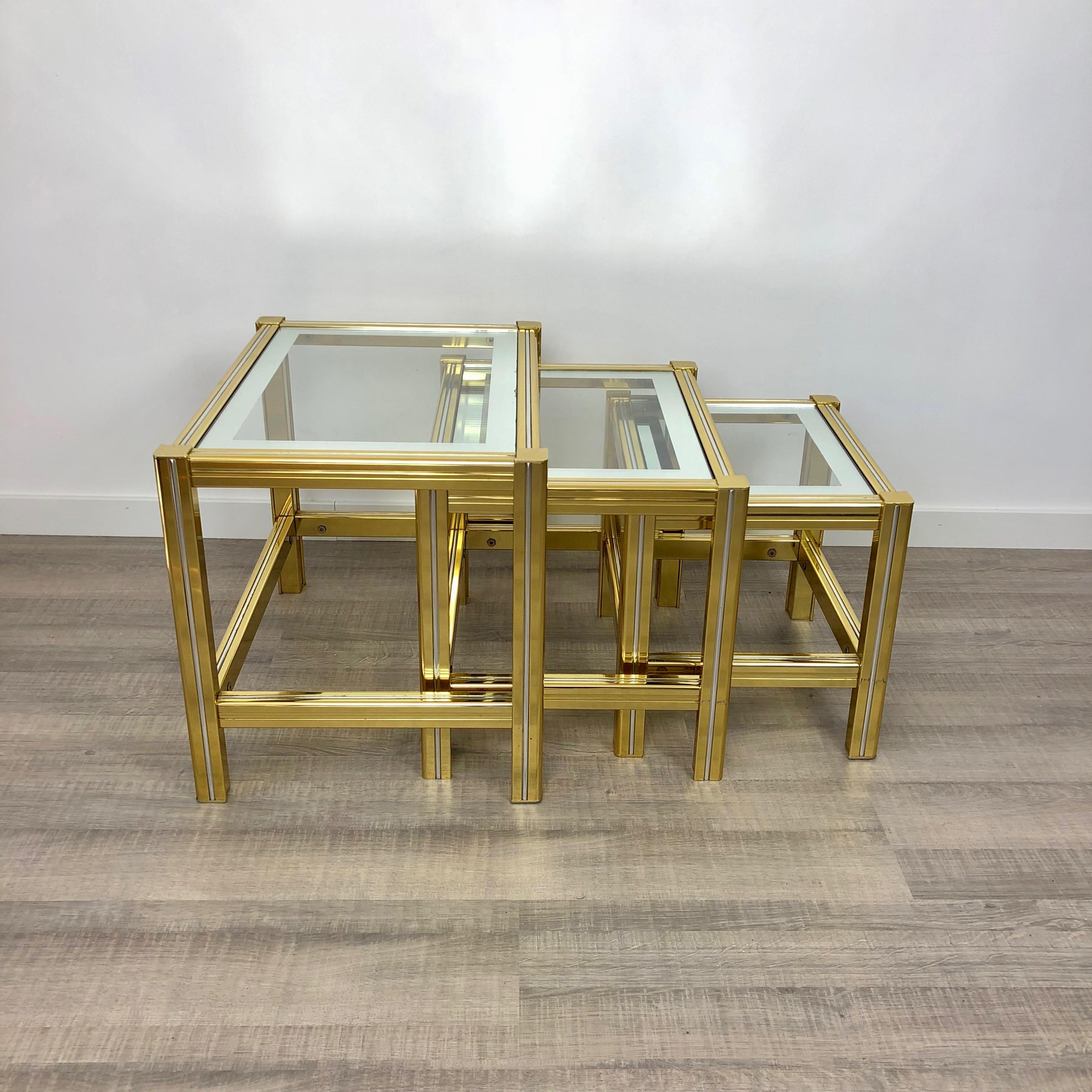 Tris of side or coffee tables in increasing dimensions made of brass, chrome and glass. A midcentury piece of Italian design.
