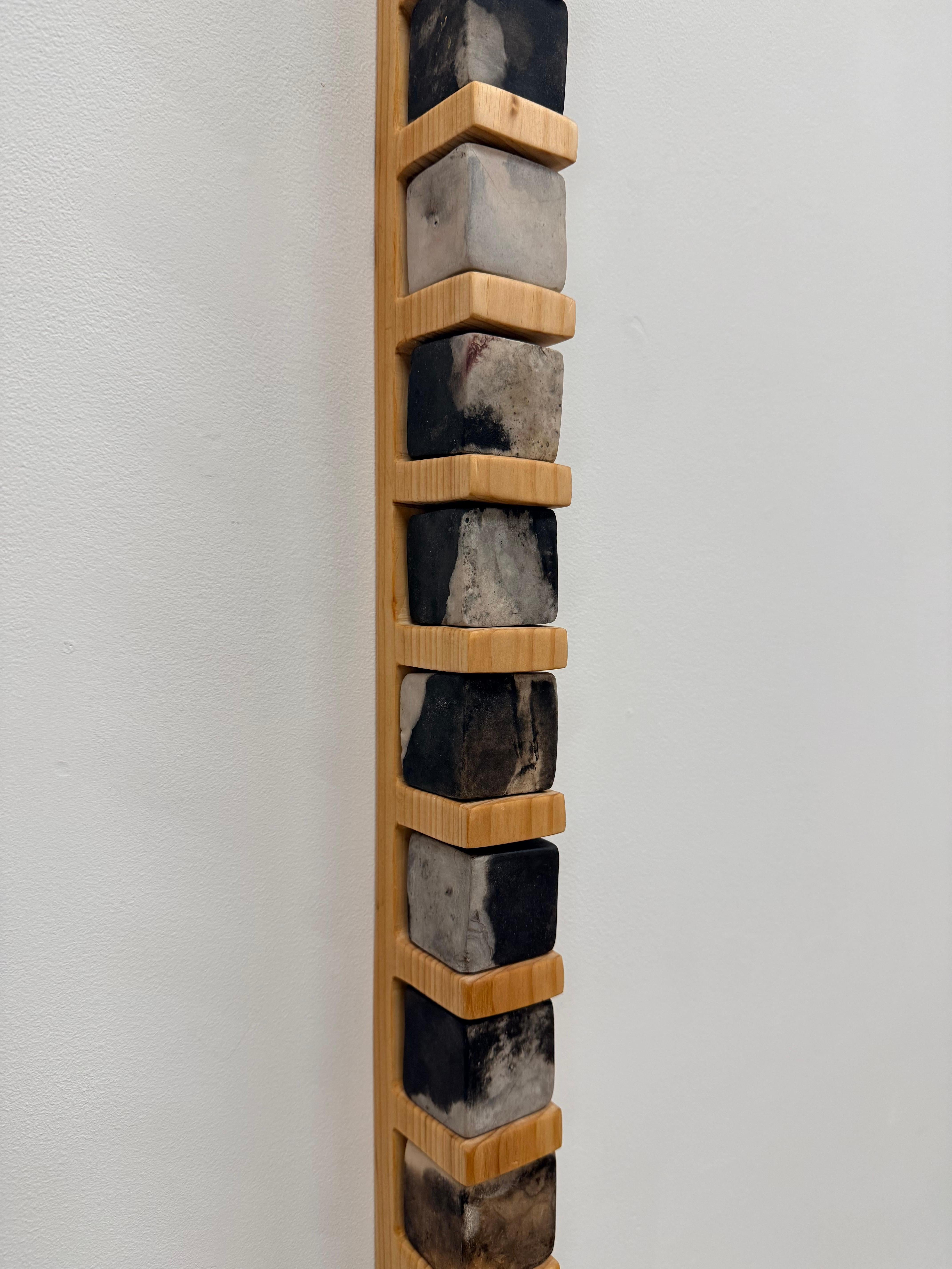 Scultura contemporanea a parete di Tristan Fitch composta da cubi di porcellana cotti in fossa su una mensola intagliata a mano in pino di provenienza locale che fa riferimento alle forme architettoniche e all'alchimia. I cubi di porcellana vengono