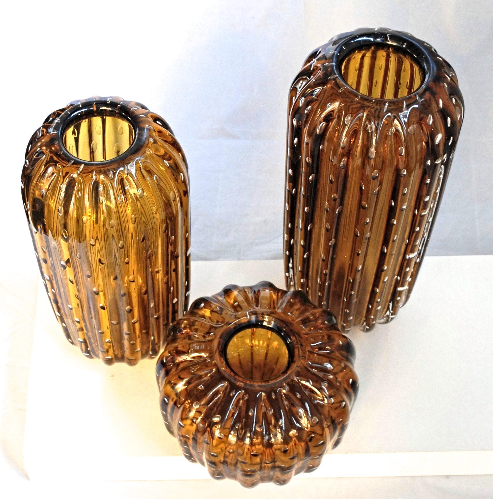 A splendid group of three vases made combining the regarding straight technique and the baloton. Shape is cylindrical and resembles the Saguaro cactus.

Deep amber coated with clear. 

Shape, design and pattern leads to a Barovier 1950s