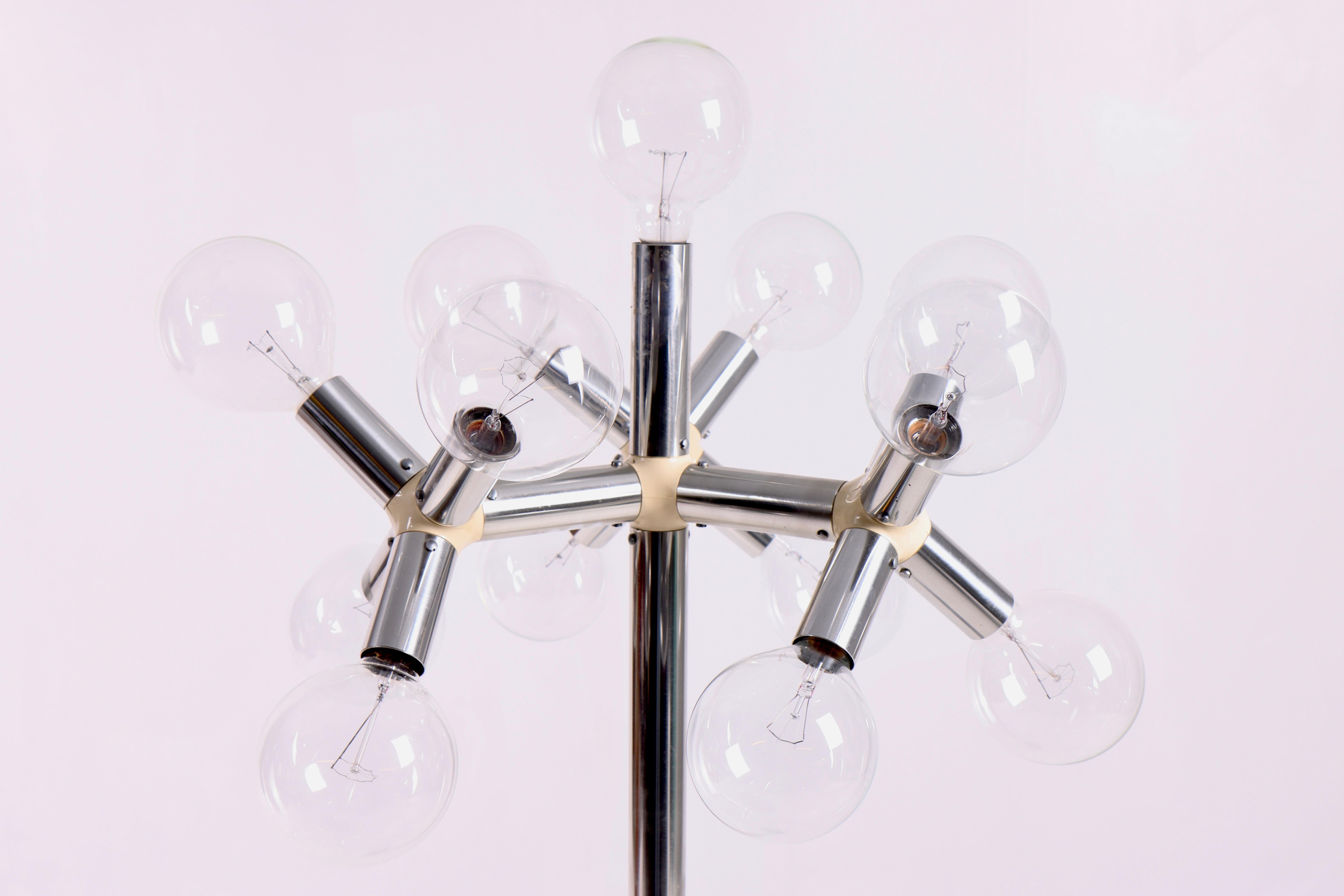 This lamp was designed by the Swiss design duo Trix and Robert Haussmann and produced by Swiss Lamps International in the 1970s. The lamp is made of metal and has a futuristic appearance with multiple visible incandescent bulbs arranged in a