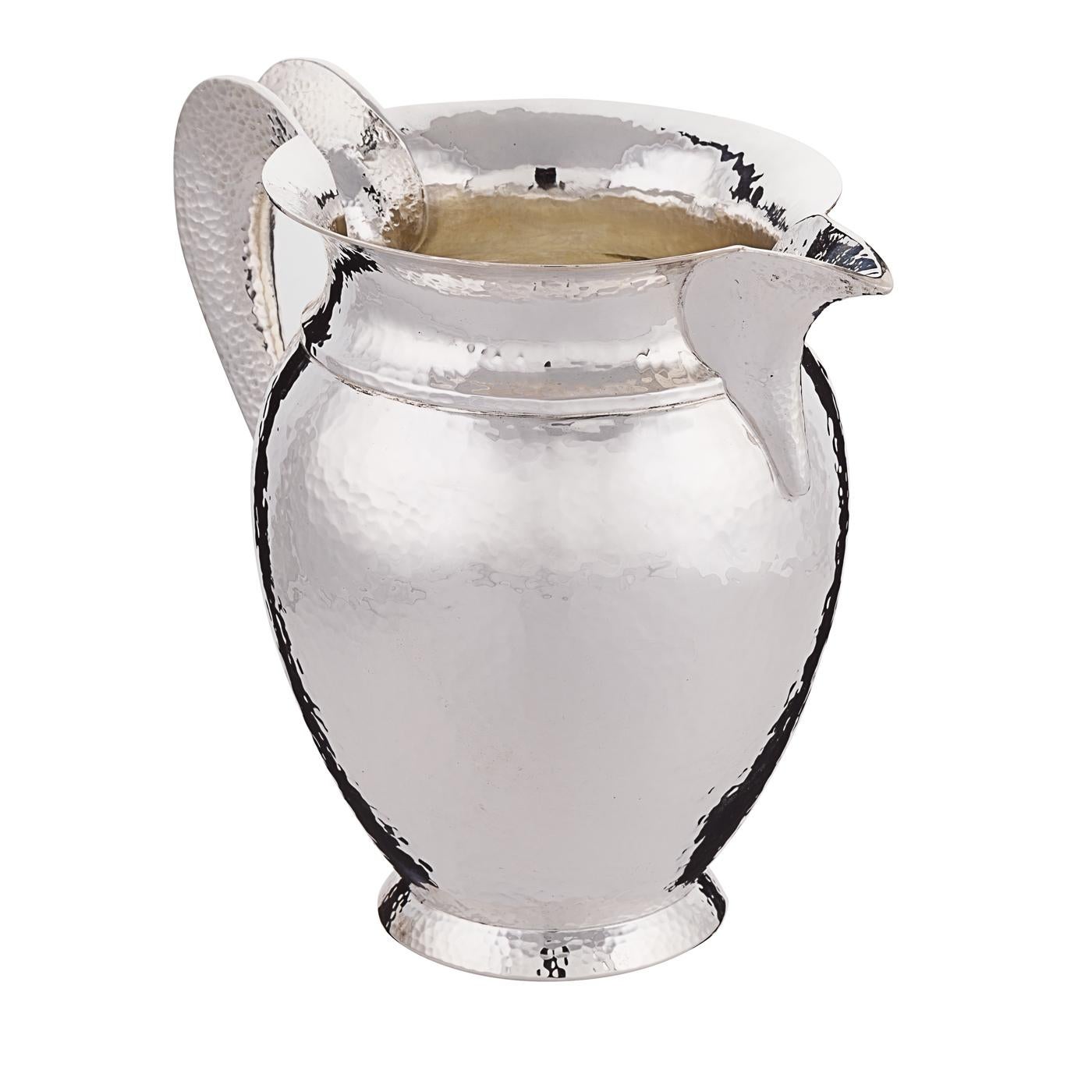 A shimmering sterling silver pitcher consummately handcrafted by the Florentine silversmith Pampaloni. The artisan was inspired by Trojan silverware for this Classic jug that, like the other pieces of the Troiana collection, is characterized by a