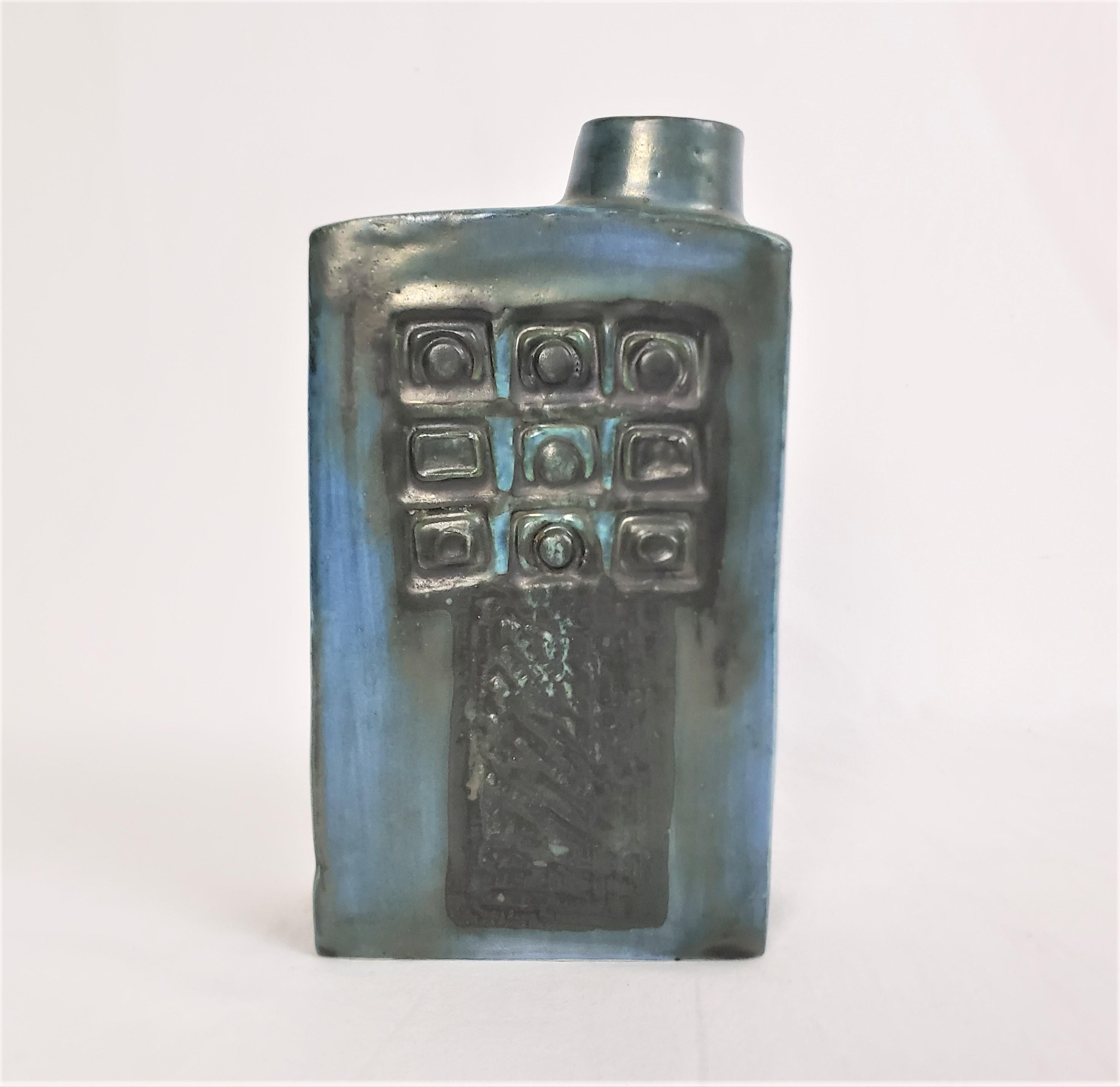 This vase was done by the well known Troika St. Ives factory of England in approximately 1960 in the period Mid-Century Modern style. This art pottery vase is done with a deep blue ground, with slip over glazes of green and black. Both the front and