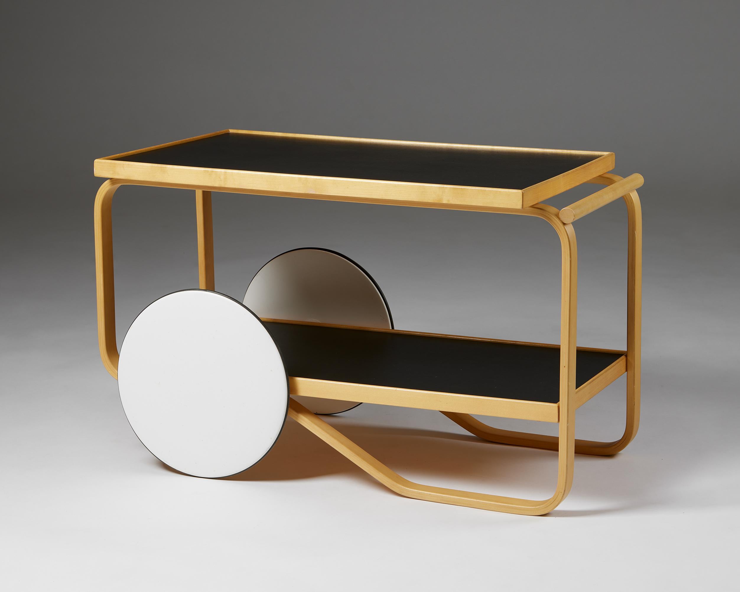 Trolley model 98 designed by Alvar Aalto for Artek,
Finland. 1950s.

Birch frame, black linoleum shelving, and white lacquered wooden wheels.

Stamped.

Measurements:
H: 56 cm / 1' 10