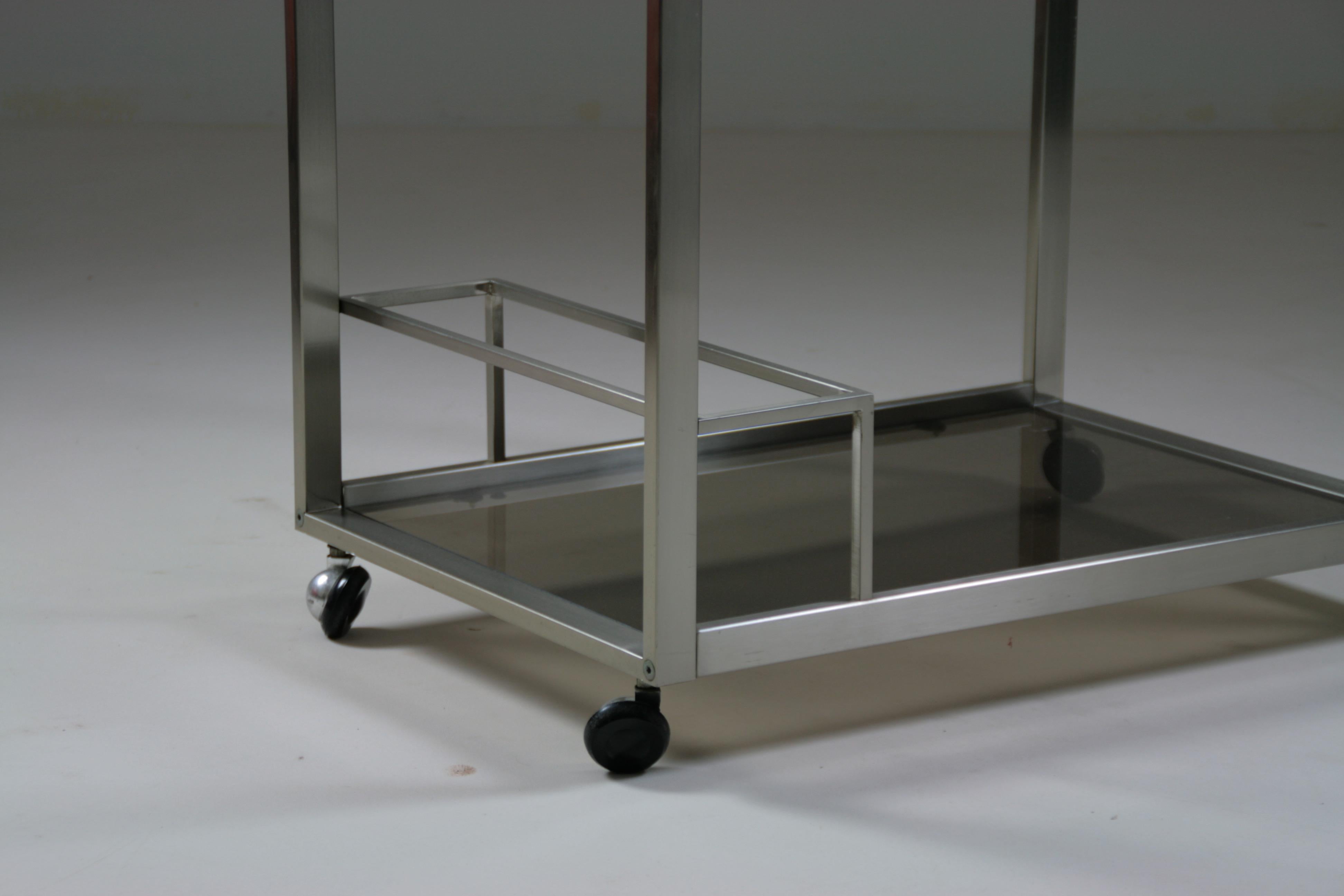 Chariot de bar ou chariot roulant à deux niveaux. Structure en métal brossé et plateaux en verre fumé. Le serveur dispose également d'un porte-bouteilles. Très bon état. Dimensions : l 66 x d 45 x h 74 cm.