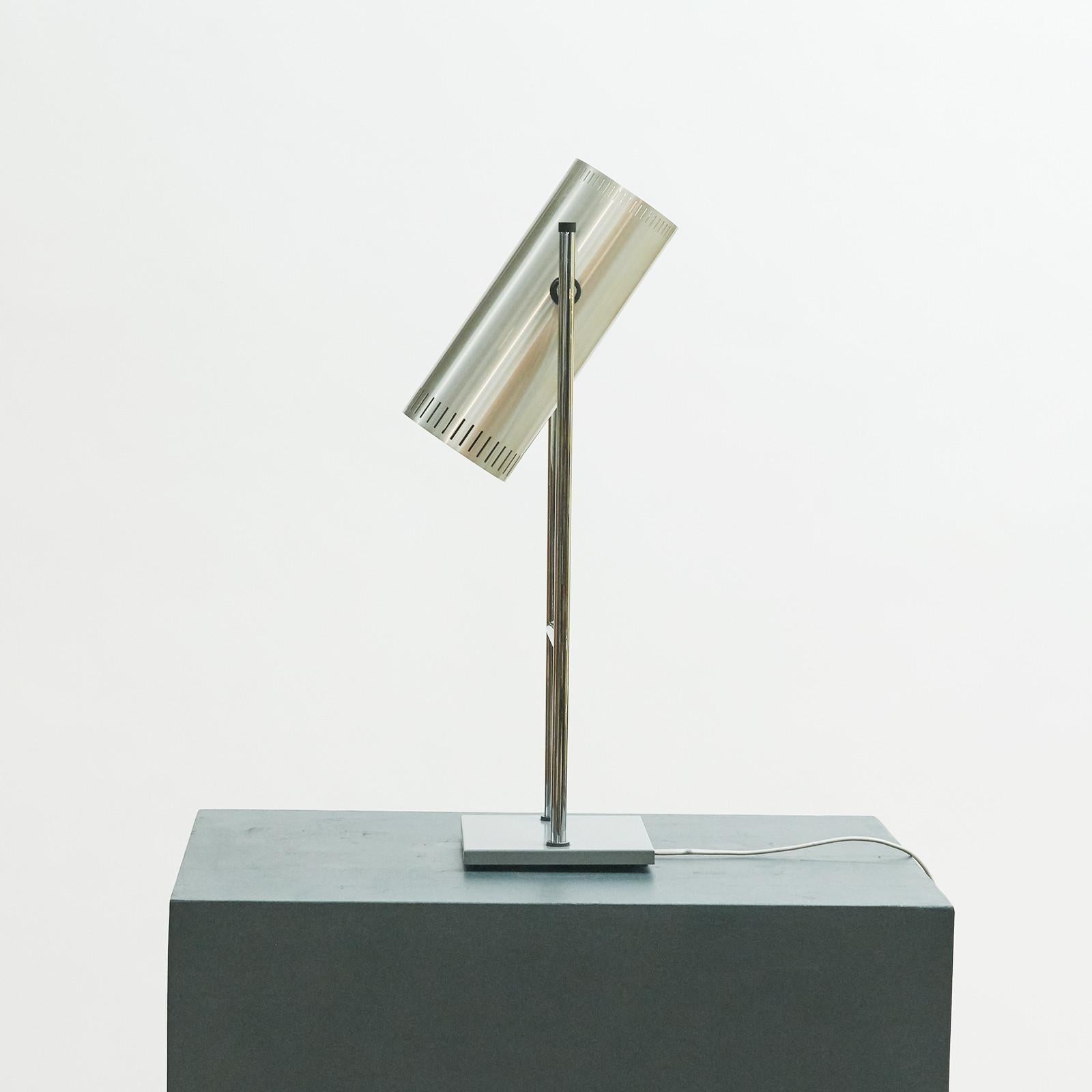 *Trombone' aluminum table / desk lamp by Jo Hammerborg for Fog & Mørup from the 1960s. 
A sleek shaped desk lamp with a square metal base, from where two aluminum lacquered stems emerge, connected by a 