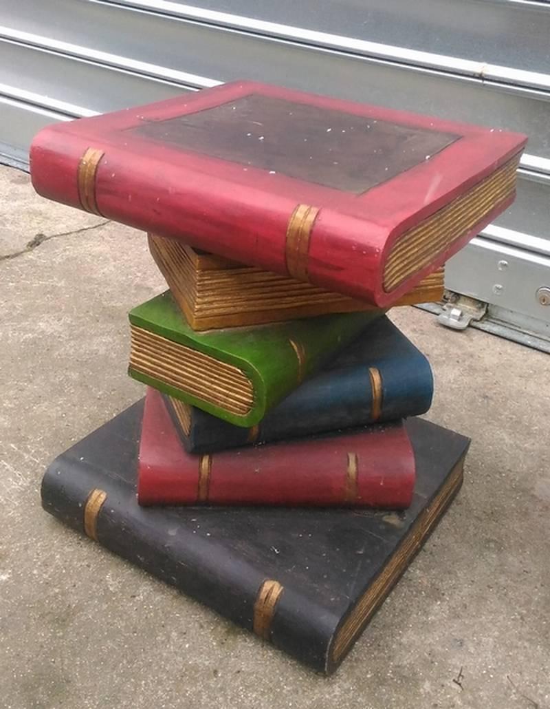 This pair of trompe-l'oeil end tables are particularly original. This work, made of painted wood, represents stacked books with black, red, yellow and green covers and golden pages. The first and last books in the stack are larger to ensure
