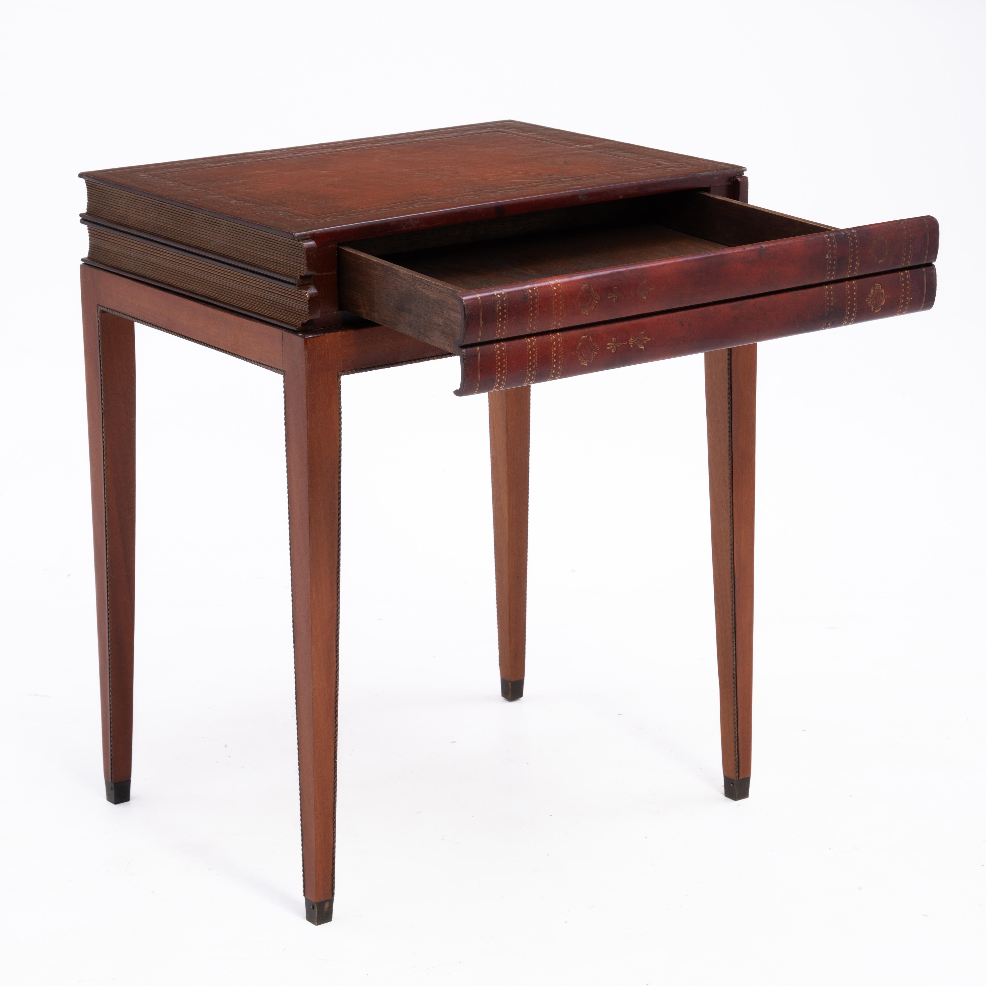 A graceful Trompe L'oeil embossed leather and mahogany book table with a single drawer table.  The delicate tapered legs end with brass capped feet There is also a carved rope detail on two sides of each leg and the bottom of the case that frames