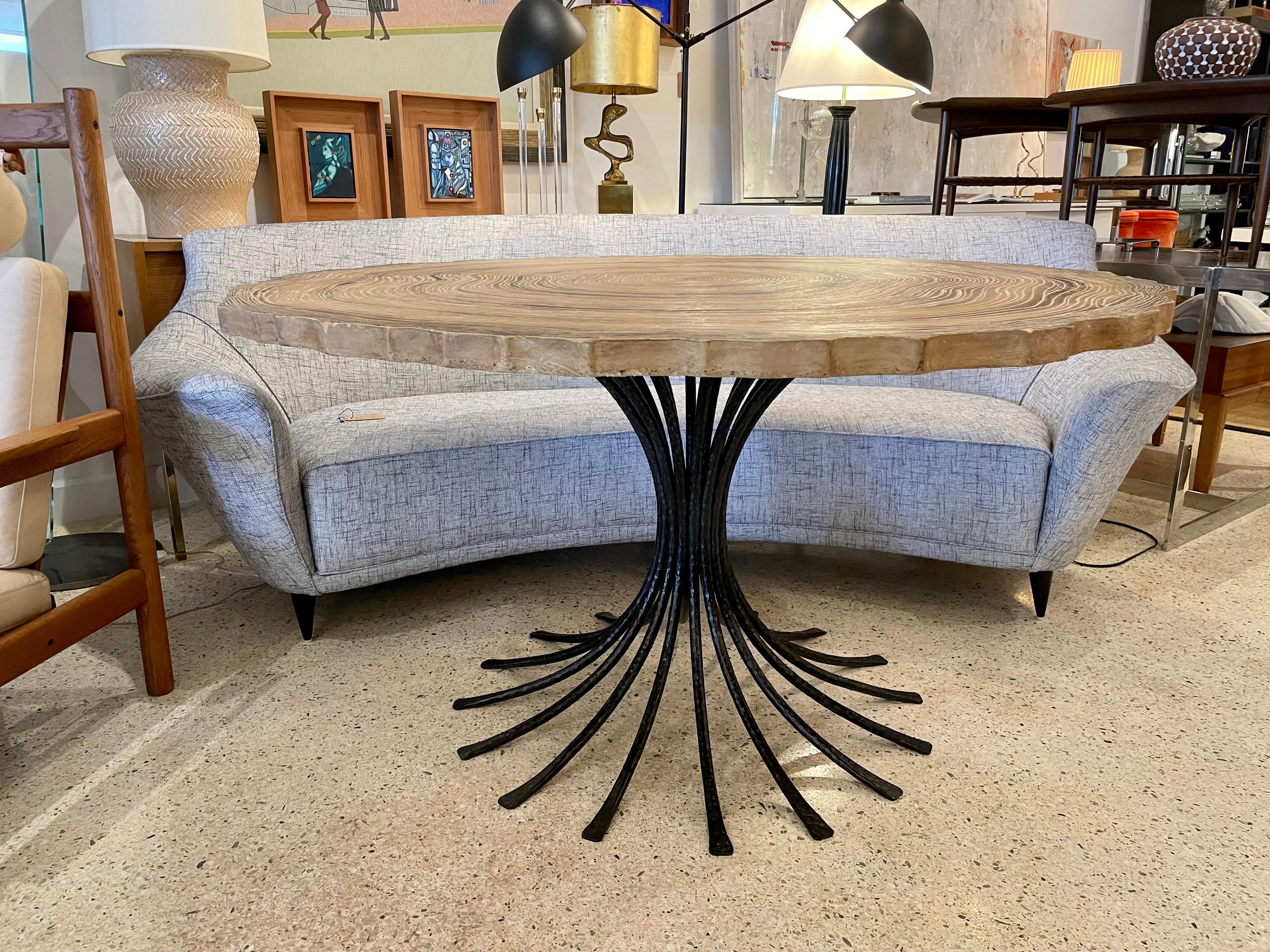 An amazingly fun and whimsical table with hammered iron base and a 1 1/2 inch thick top like no other. Painted top as a slice of a mighty redwood, the age rings and variations of wood tones are carved in to the stone to depict a realistic feel of a