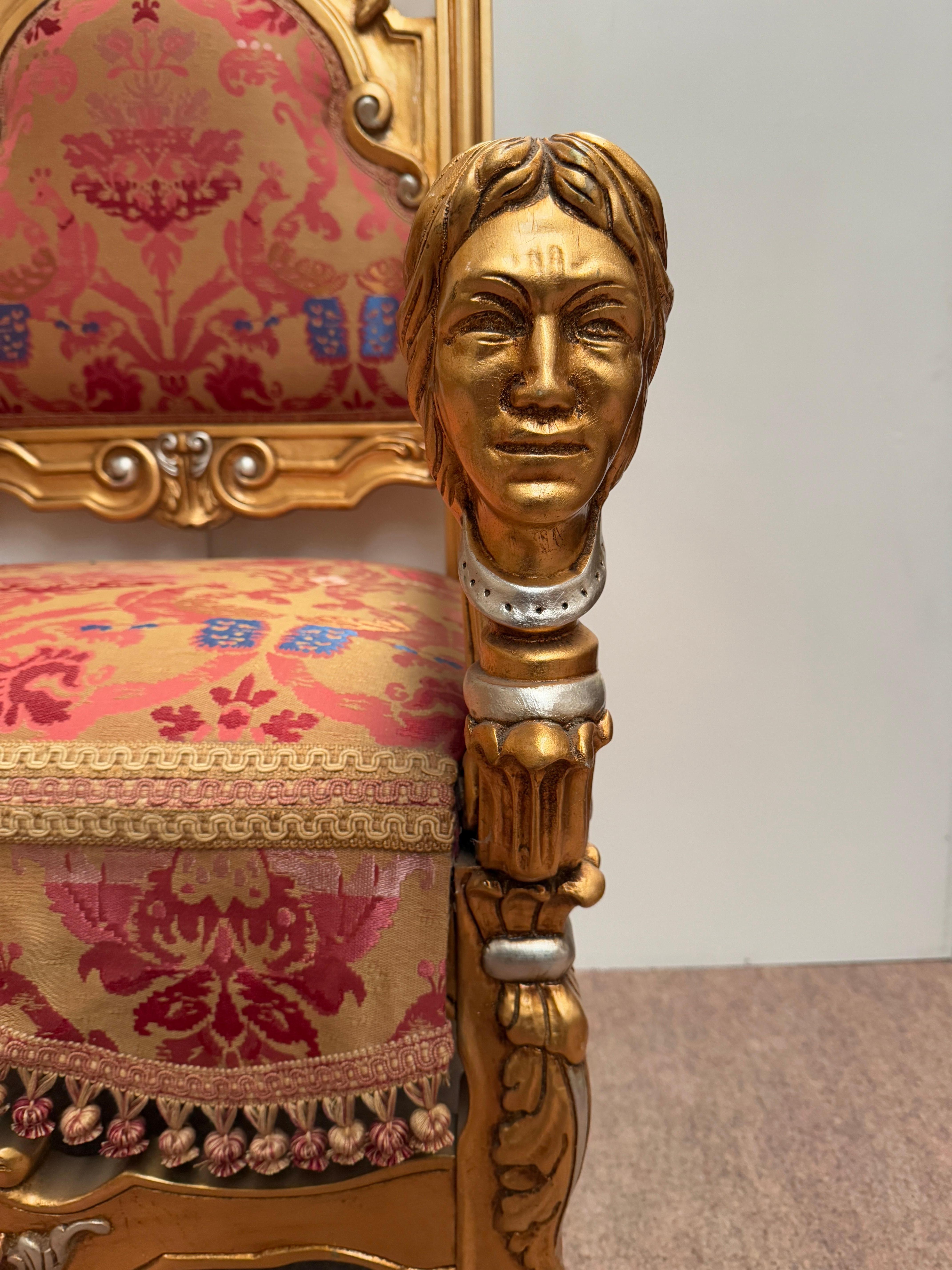 Imponente y escénica, esta silla trono de estilo barroco es una verdadera obra maestra de la artesanía. Con su marco de madera maciza dorada con pan de oro, sus refinadas tallas y sus detalles únicos (leones rampantes, cabezas talladas, patas de