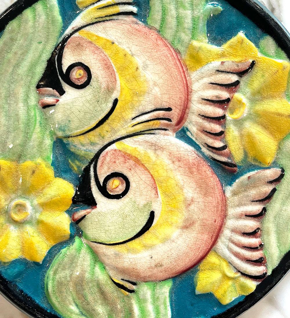 An especially rare piece of high style Art Deco ceramics by the renowned Cowan firm just outside Cleveland, this vividly-glazed trivet depicts a pair of plump tropical fish swimming in a forest of swaying seaweed. Cowan only operated for a short
