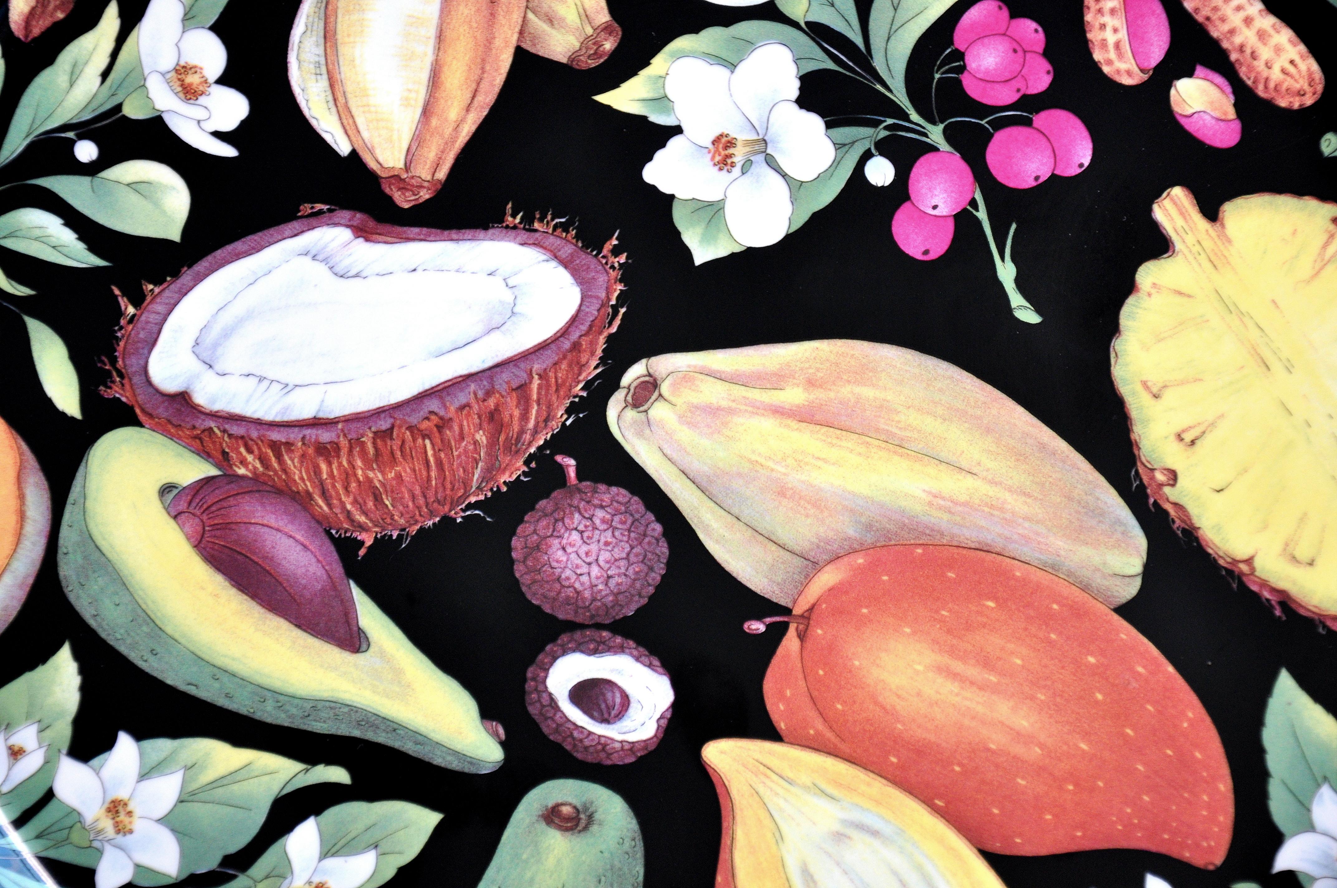 Skurriles rundes Porzellantablett von Philippe Deshoulières für Limoges aus der auslaufenden Kollektion Fruit Tropicaux Fond Noir. Die flache Servierplatte ist mit tropischen Früchten, Nüssen und floralen Motiven in Trompe L'Oeil-Technik auf