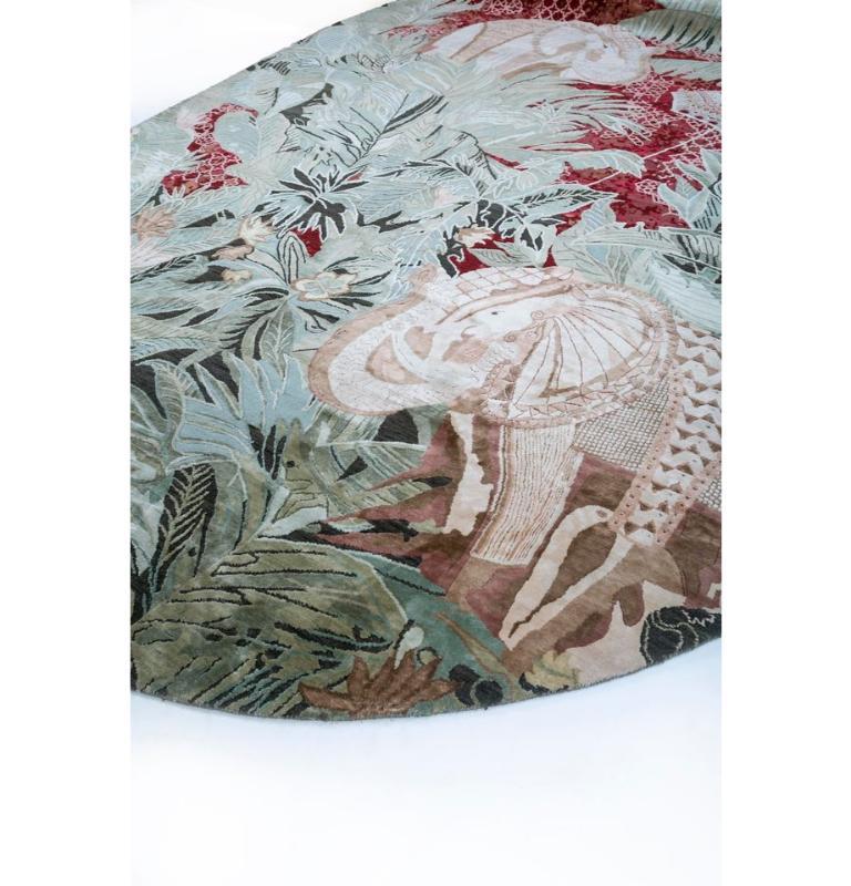 This lush forest inspired hand knotted rug from our Inde Rose is a masterpiece that effortlessly combines modern design with artisanal craftsmanship. This rectangular rug features a mesmerizing lush forest pattern with elephants in shades of surf