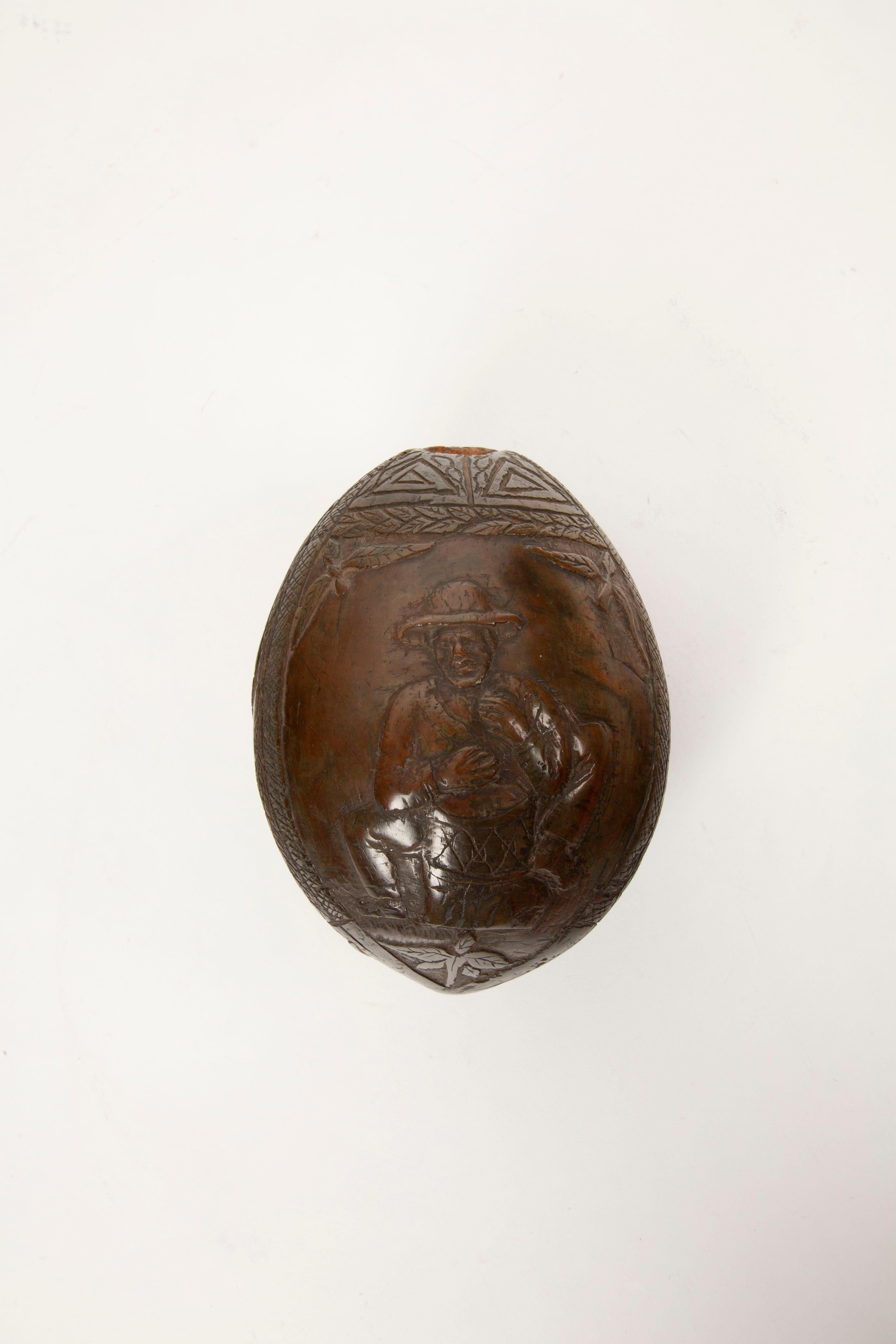 This rare mid-19th-century French Colonial carved coconut bugbear flask is a remarkable artifact that highlights the ingenuity and craftsmanship of sailors, soldiers, or prisoners of war during extended sea voyages. Carefully carved from a green