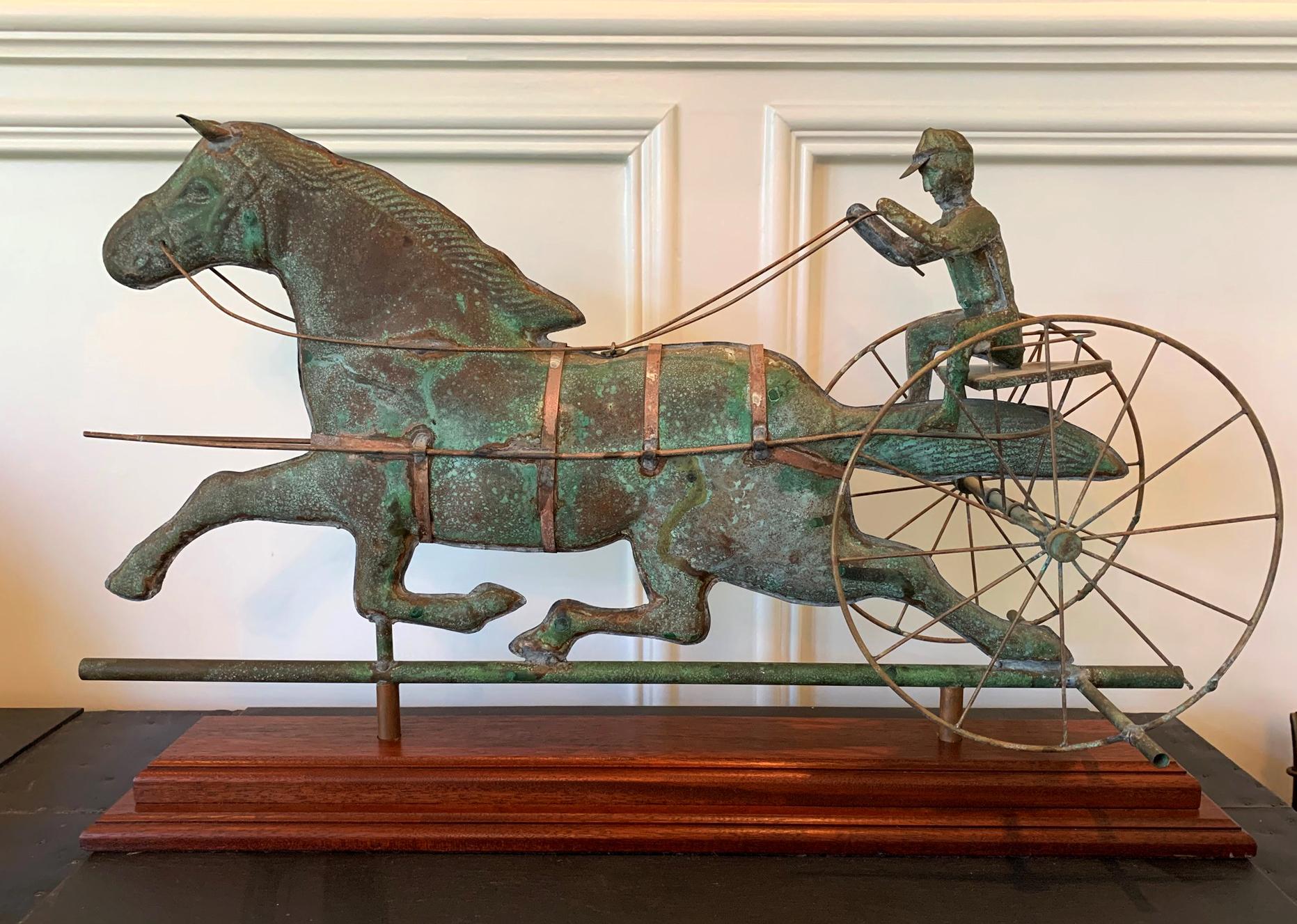 A copper weathervane of sulky on a two-wheel buggy driving a trotting horse. The piece is of a vivid three dimensional full body construction and displayed on a museum quality custom stand. The weathervane, likely made toward the end of the 19th