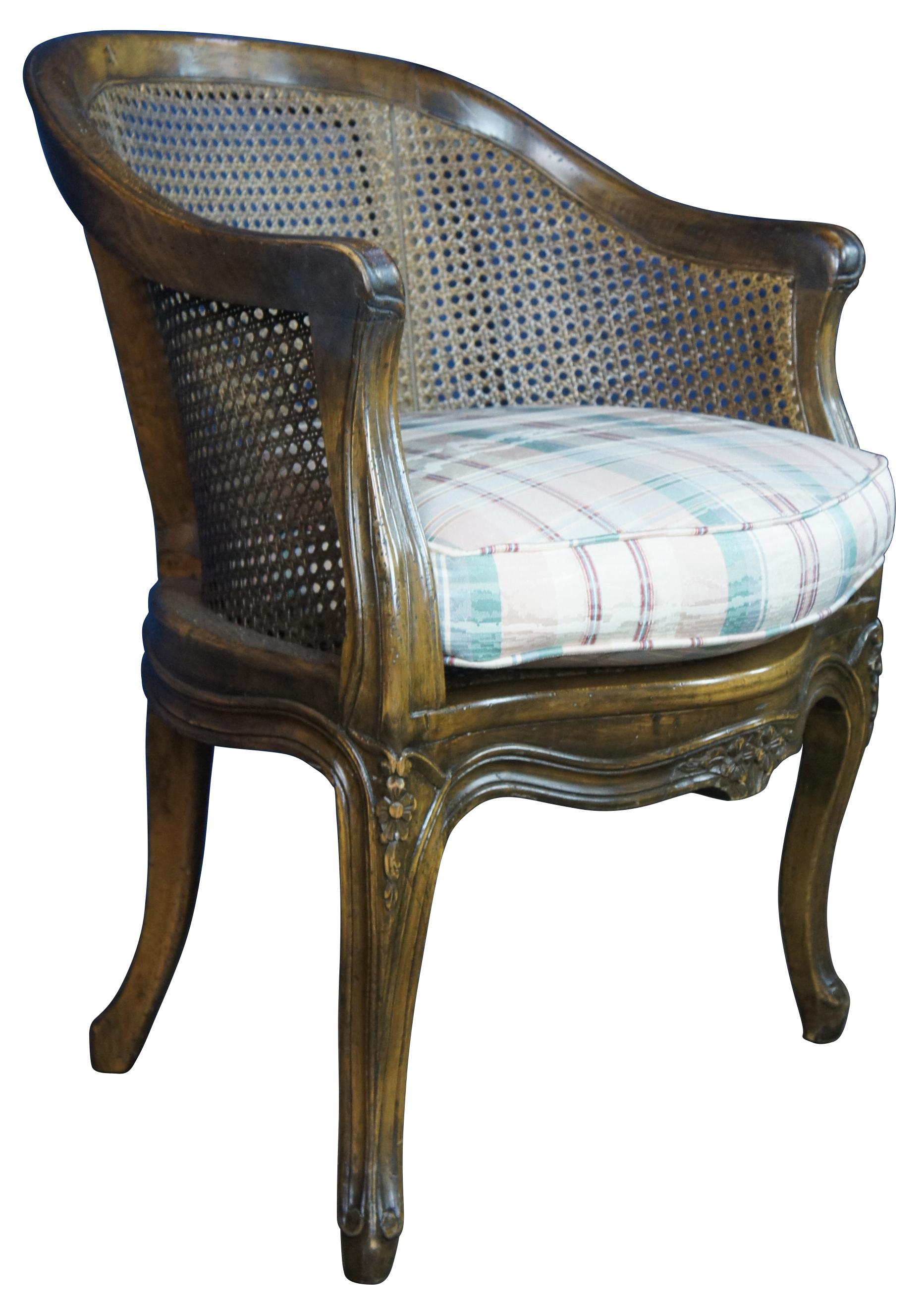 Vintage French Louis XVI style bergere club or lounge chair by Trouvailles Inc of Watertown, Ma. Made of walnut featuring serpentine form with round caned back and carved floral accents.
    