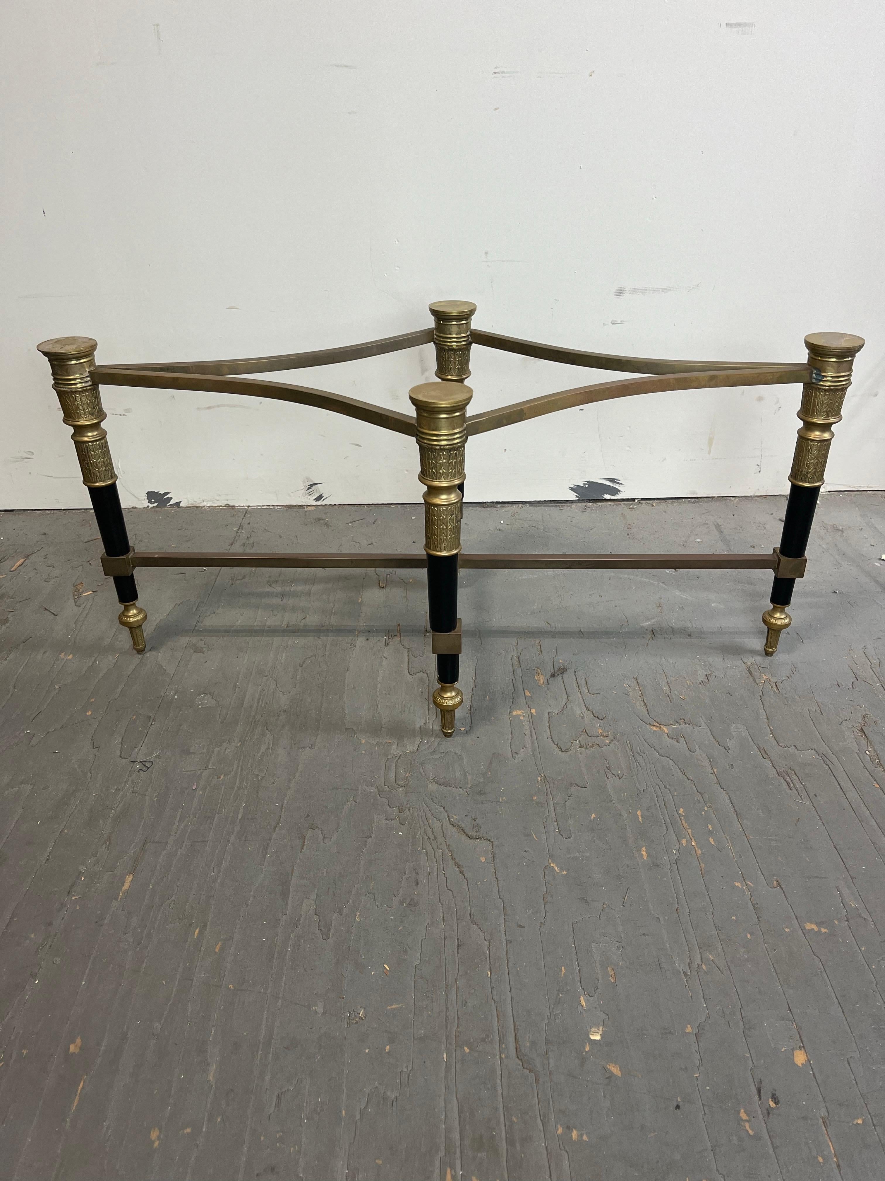 This stylish neoclassical campaign style, oval-form, cocktail table dates to the 1970s and was designed and fabricated by the American firm of Trouvailles. The piece is fabricated in steel, brass and Ogee beveled glass. 