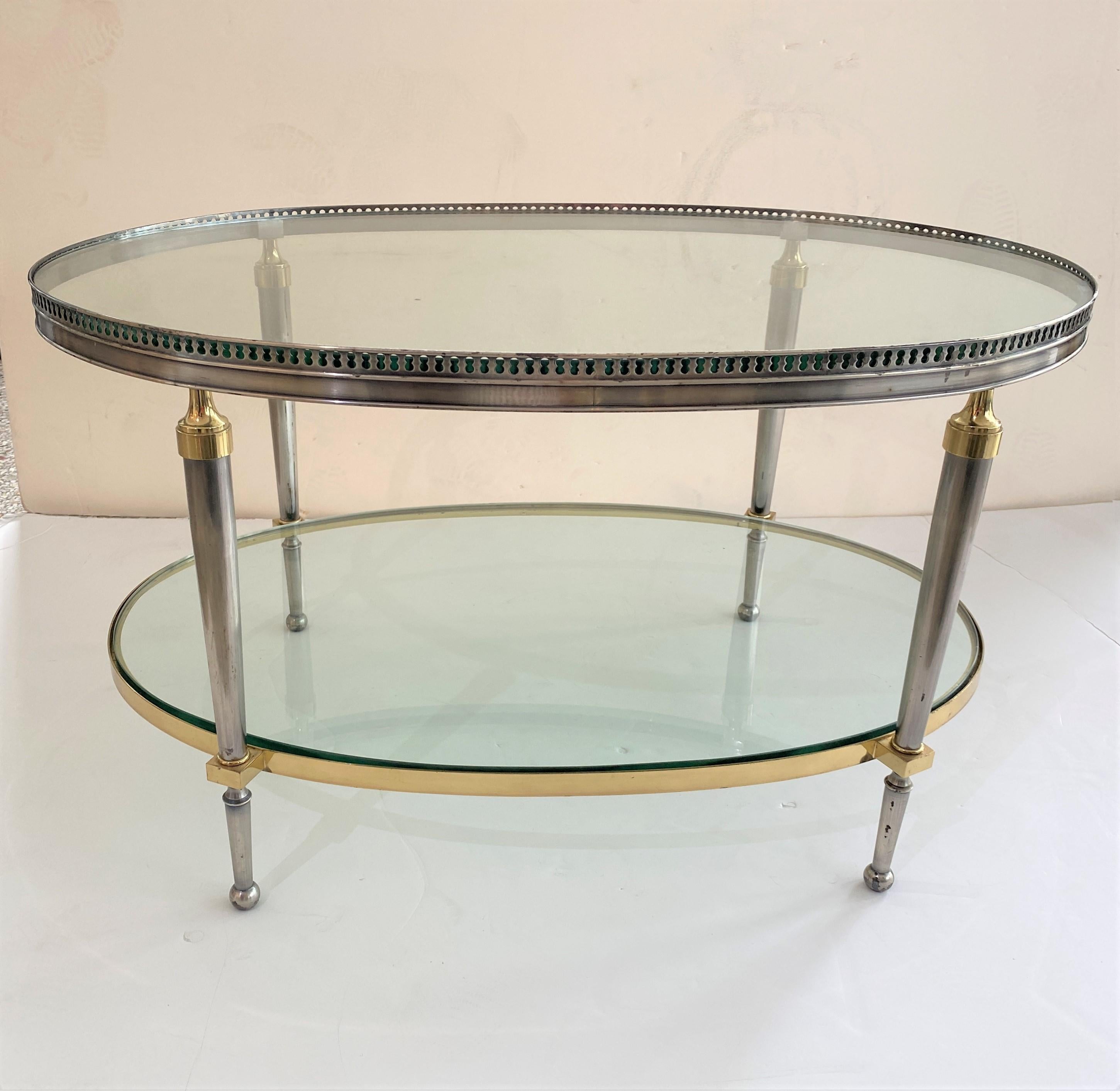 This stylish campaign style, oval-form, two-tiered cocktail table dates to the 1970s and was designed and fabricated by the American firm of Trouvailles of New York City. The piece is fabricated in steel, brass and glass.

Note: We have this table