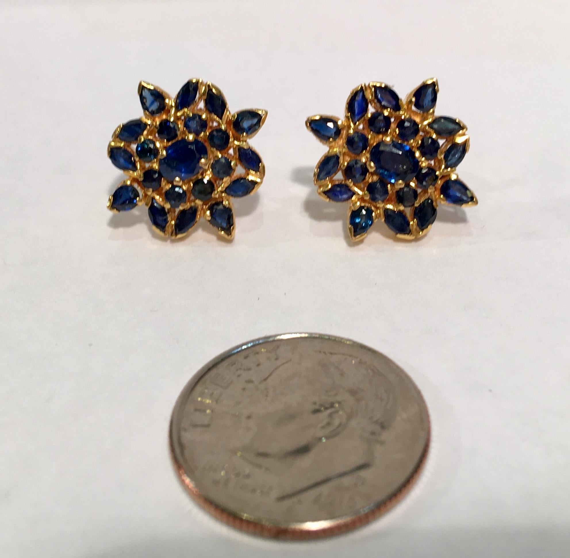 Elegantly proportioned and easy to wear 22 karat yellow gold estate earrings feature prong, tension and pave set oval, round, marquise and pear cut blue sapphires arranged in stylized snowflake or flower designs.  Posts feature screw backs for