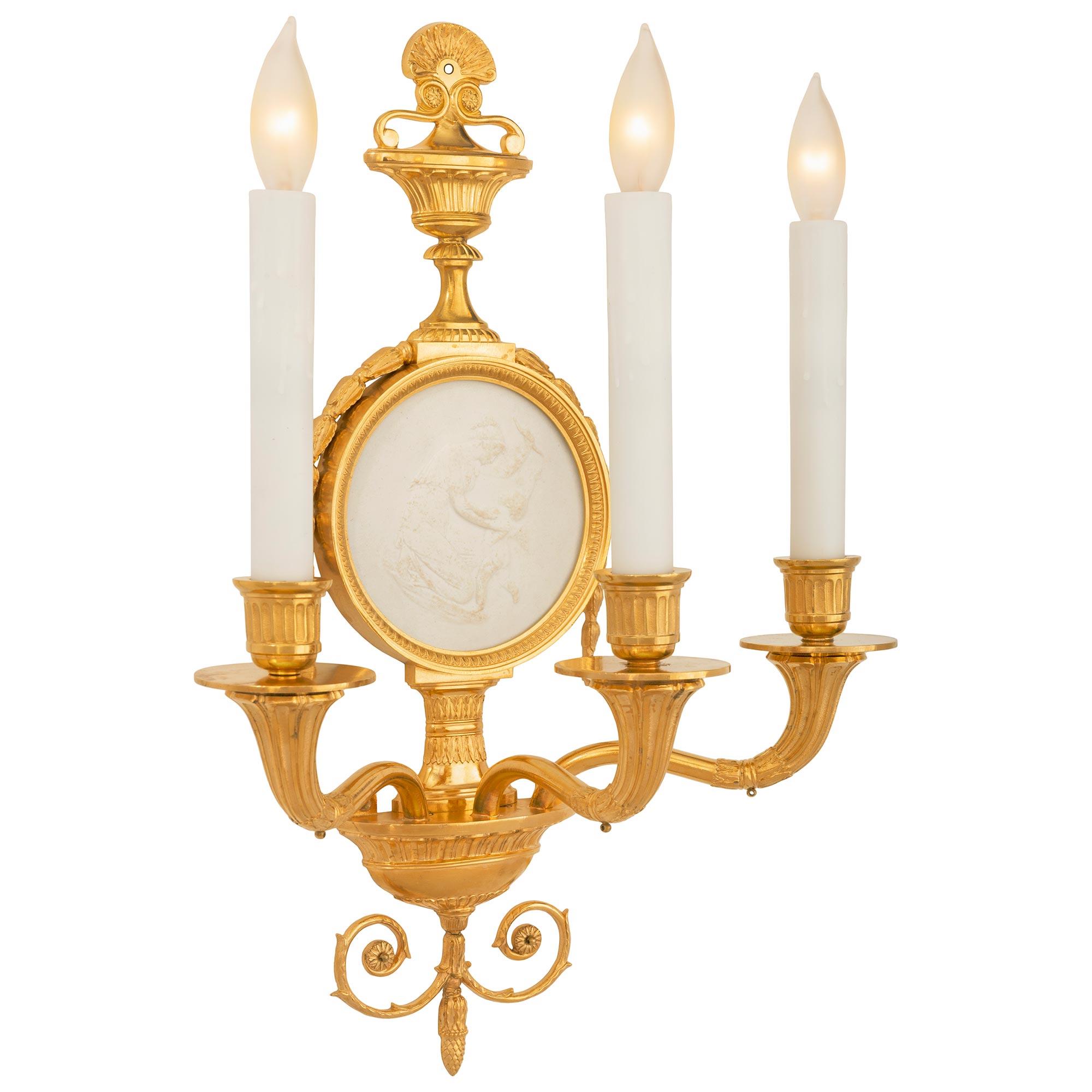 A beautiful and most elegant true pair of French 19th century Neo-Classical st. Biscuit de Sèvres Porcelain and ormolu sconces. Each three arm sconce is centered by fine bottom elongated acorn finials below most decorative scrolled foliate Rinceau