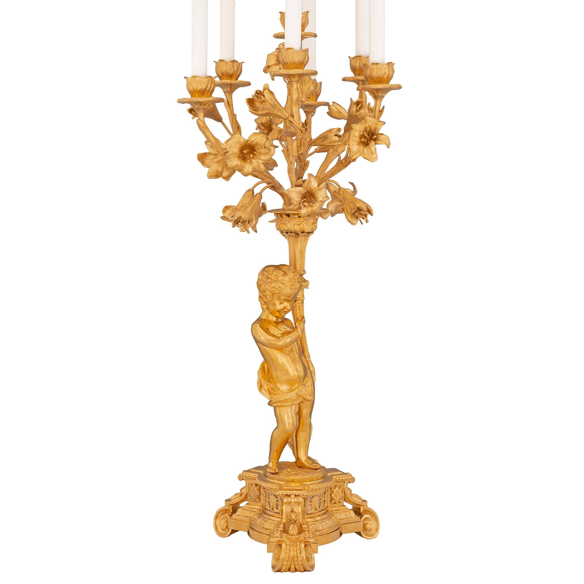 A striking large scale true pair of French 19th century Louis XVI st. Belle Époque period ormolu candelabra lamps. Each seven arm lamp is raised by an elegant triangular shaped base with concave sides and cut corners displaying superb most