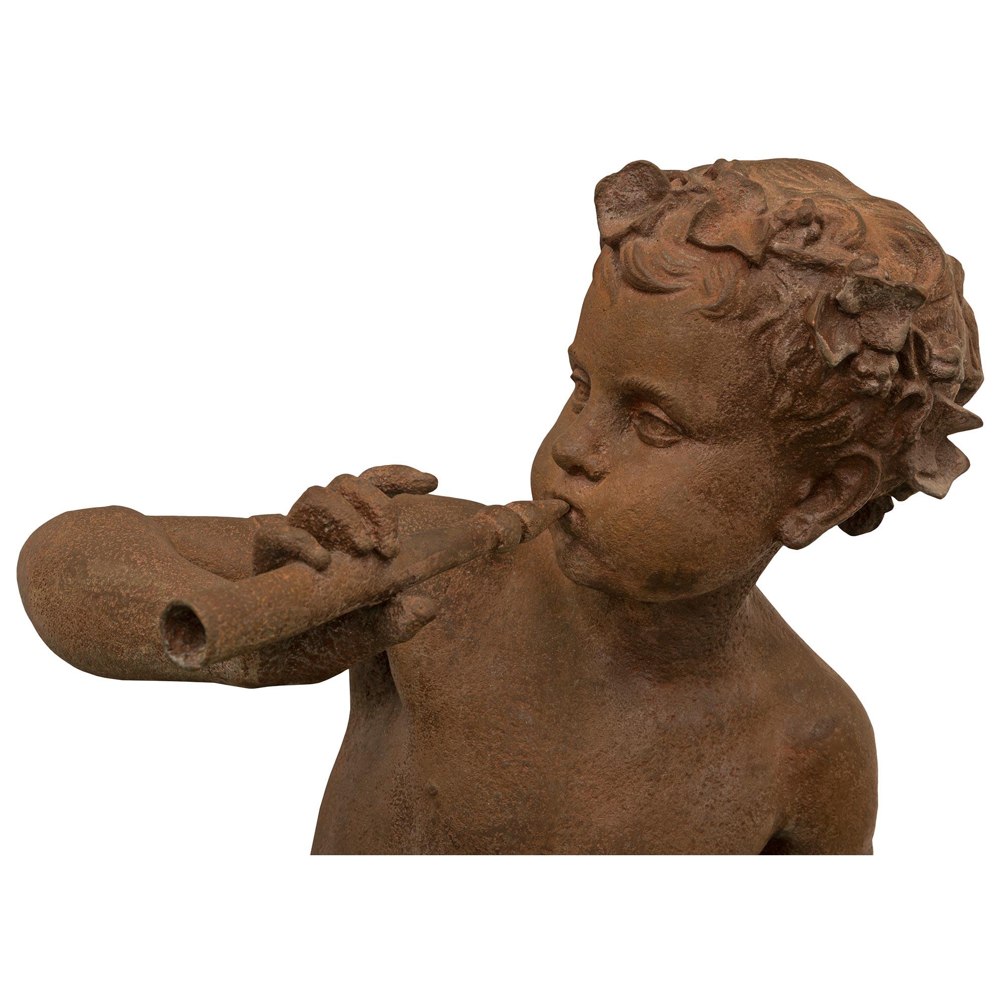 A beautiful and very high quality true pair of French 19th century cast iron statues of two young boys playing flutes signed A. Durenne sommevoire. Each statue is raised by a circular base and depicts charming young boys joyously dancing and