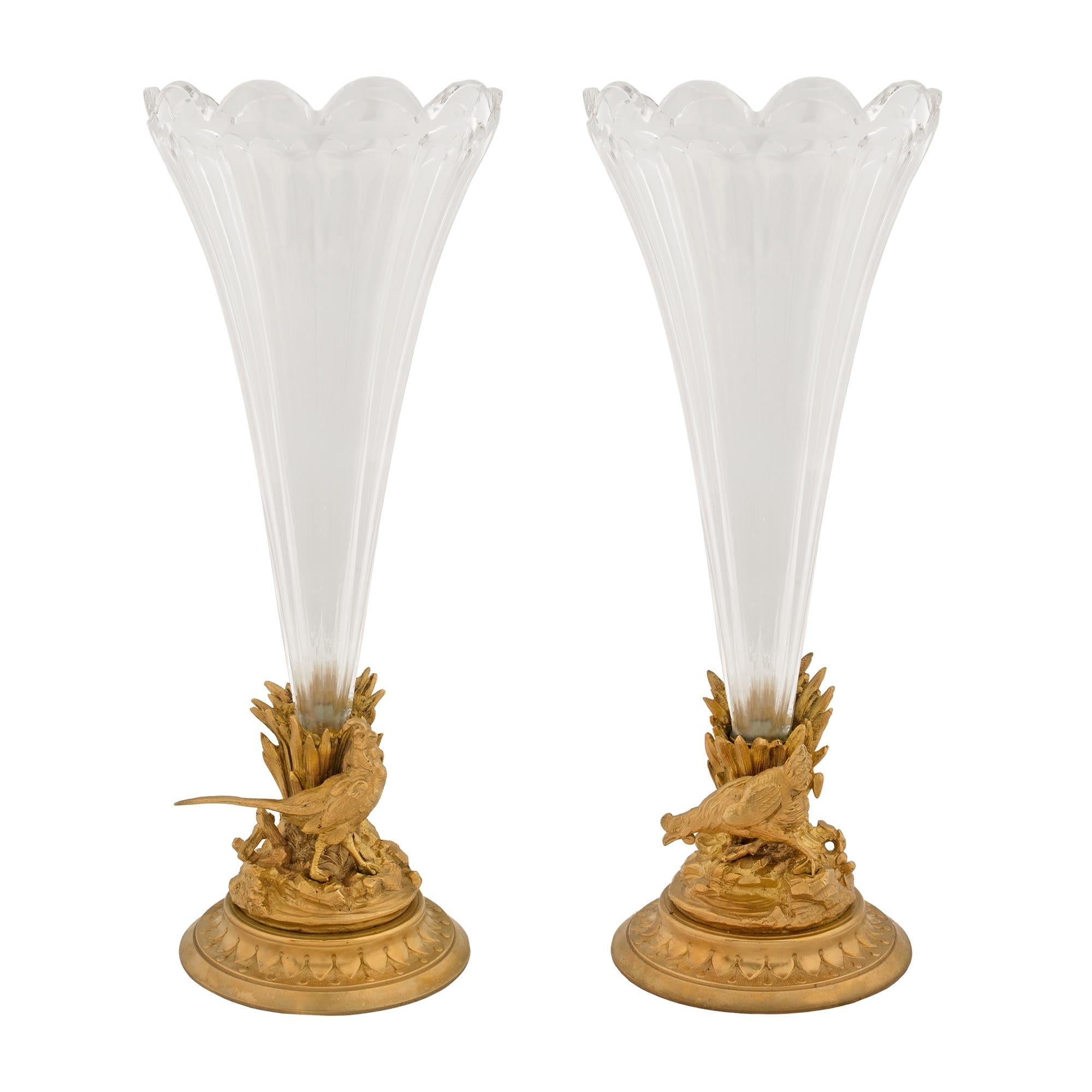 Une paire de vases en cristal et bronze doré de Baccarat du 19ème siècle. Chaque vase est surélevé par une base circulaire mouchetée avec un motif décoratif enveloppant. Chaque vase présente un design impressionnant et richement détaillé, semblable