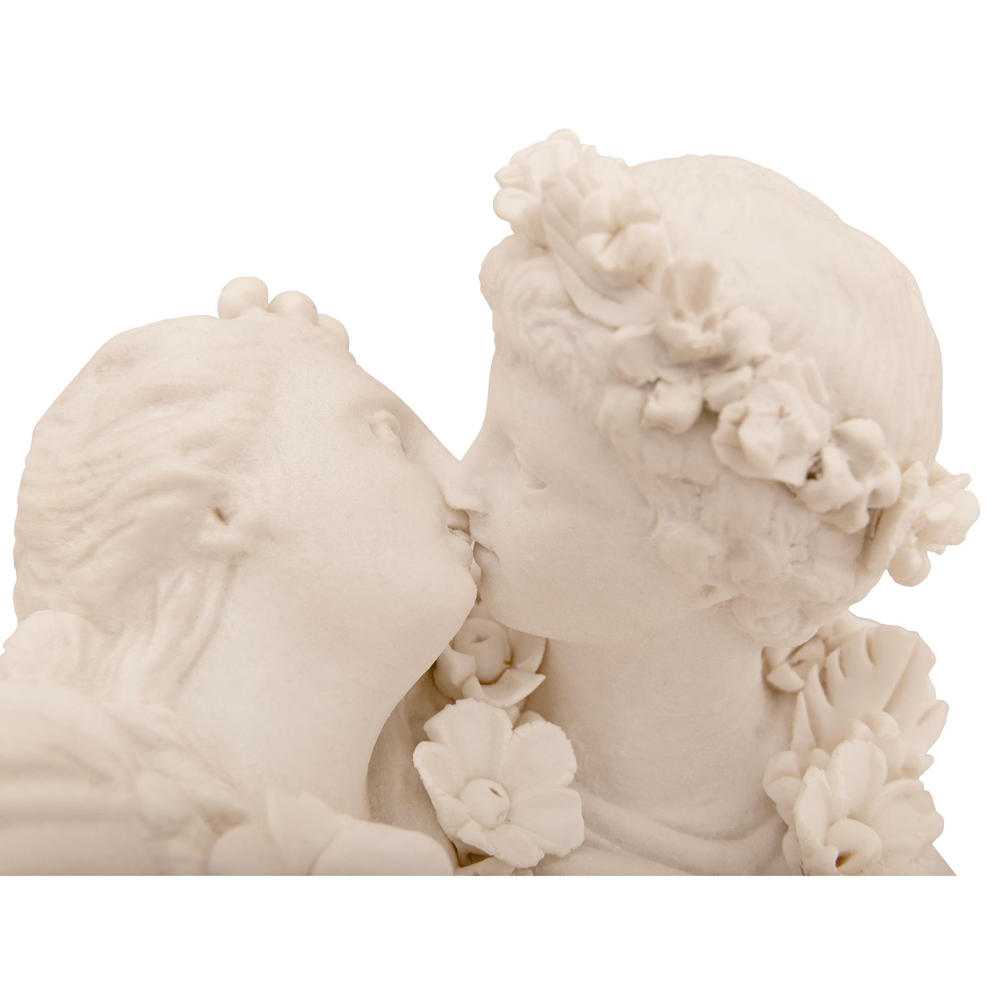 A lovely and affectionate true pair of French 19th century Louis XVI st. Alabama Rose Marble, Ormolu, white Carrara marble, and Bisque Porcelain statues entitled 'Le Baiser Donné et Le Baiser Rendu'. Each bust sculpture is raised by a square block