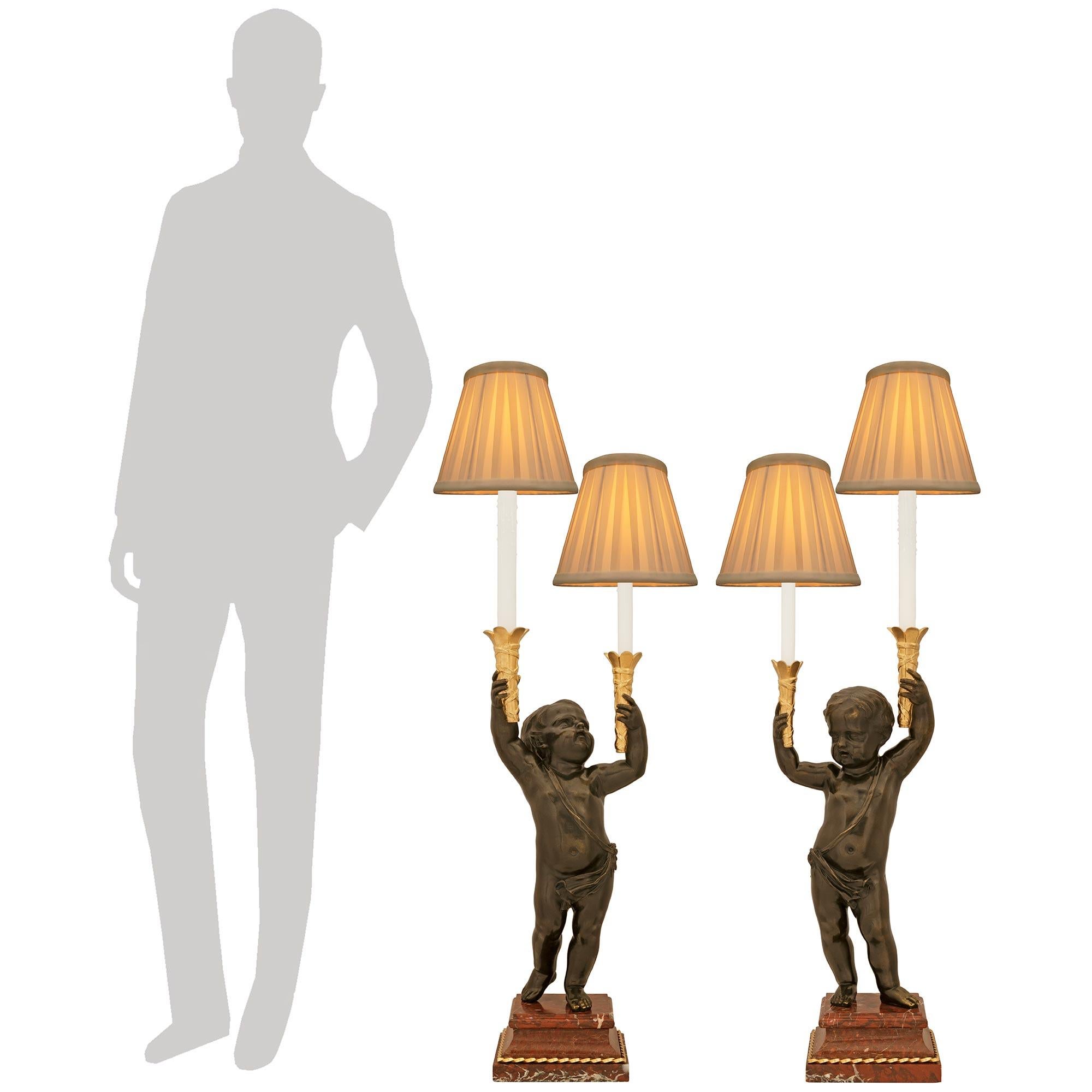 Encantadora pareja de lámparas francesas del siglo XIX de bronce patinado, mármol Rouge Griotte y Ormolu. Cada encantador candelabro electrificado se eleva sobre un zócalo cuadrado de mármol Rouge Griotte adornado con una banda de cuerda torcida de
