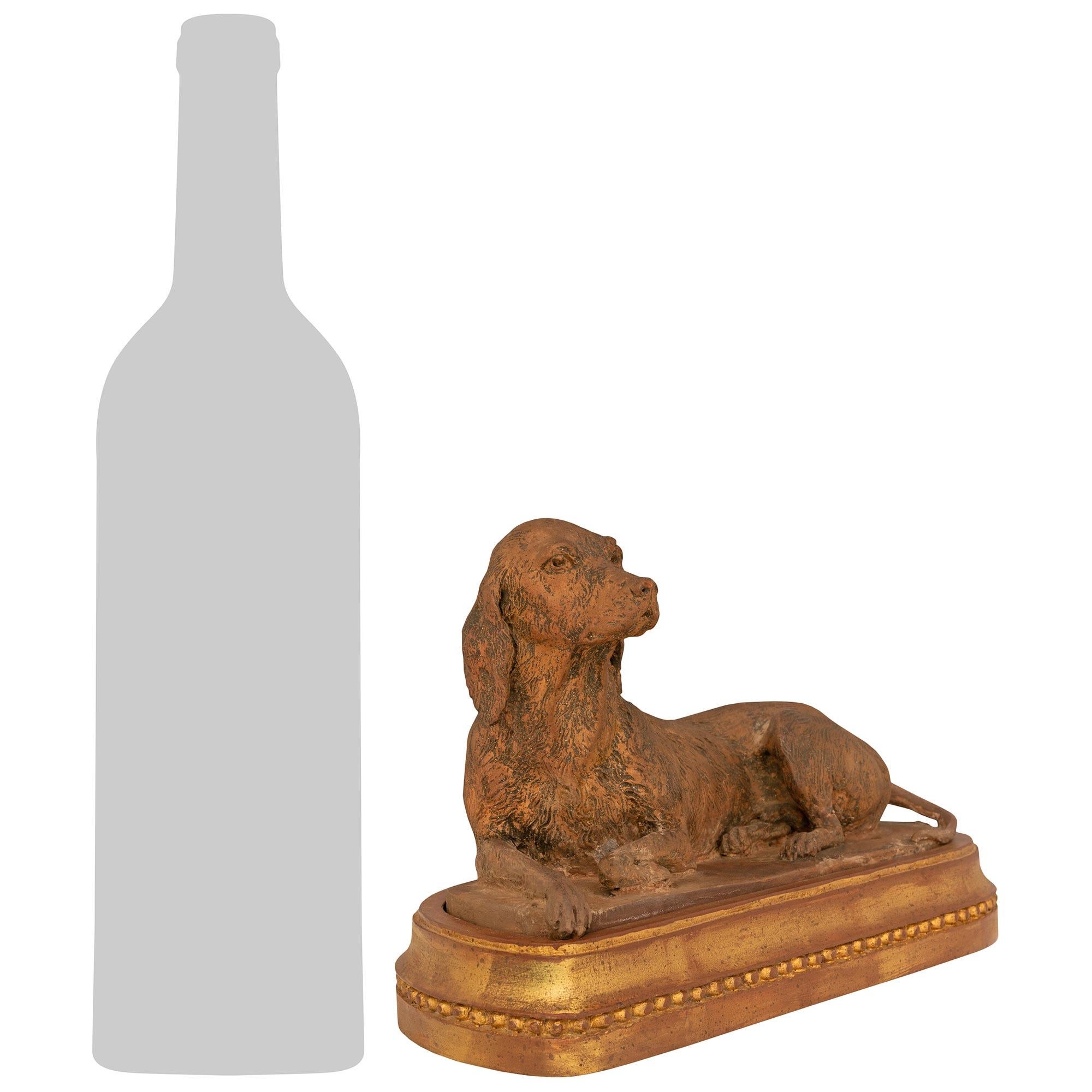 Ein hübsches, echtes Paar französischer Hundestatuen aus Giltwood und Terrakotta aus dem 19. Jede Statue steht auf einem ovalen Sockel aus Giltwood mit gesprenkelten Rändern und einem gezackten Band um die Basis. Die Hunde liegen auf der Seite und