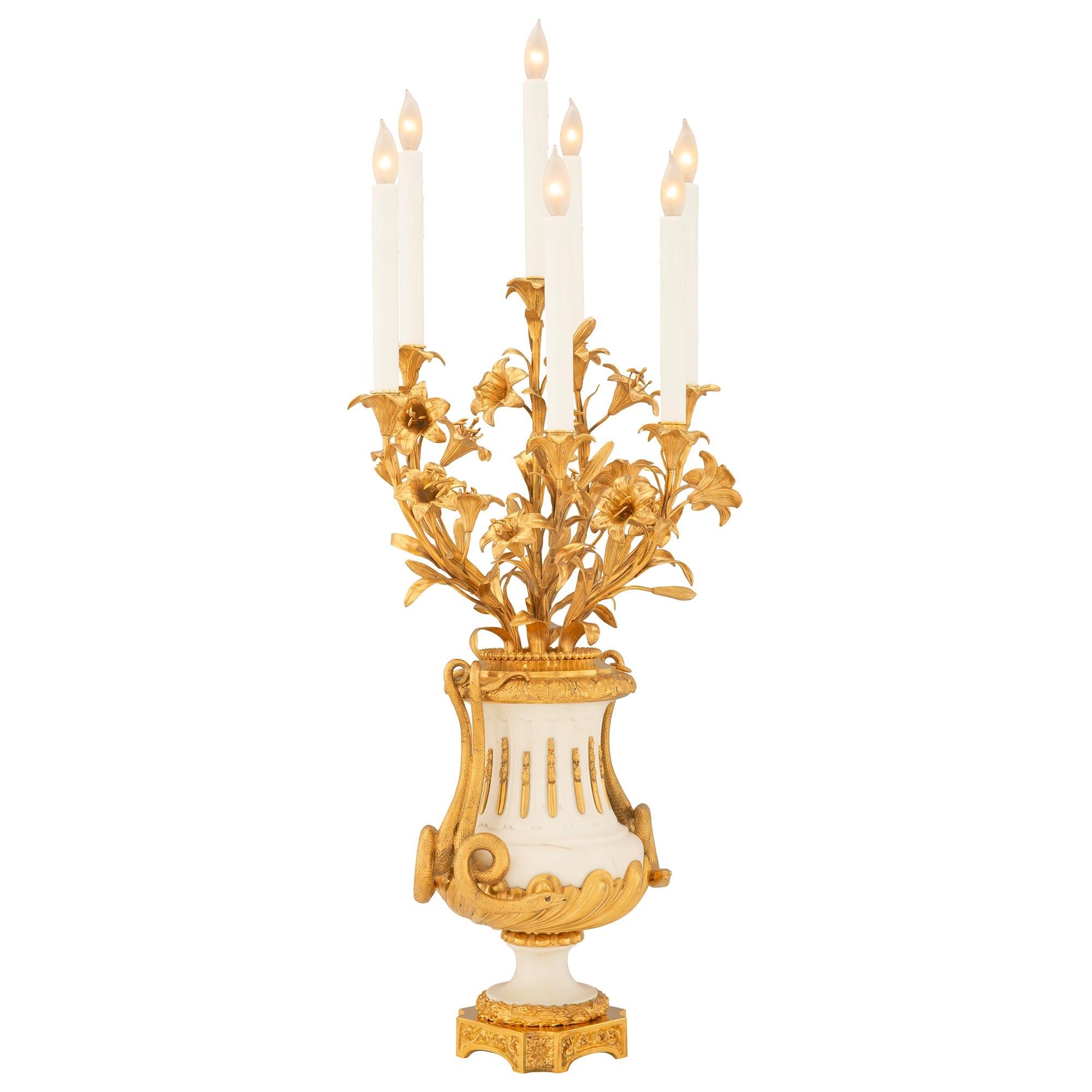 An impressive and very high quality true pair of French 19th century Louis XVI st. ormolu and white Carrara marble candelabra lamps. Each seven arm lamp is raised by an elegant square base with cut corners, beautiful block rosettes, arched front