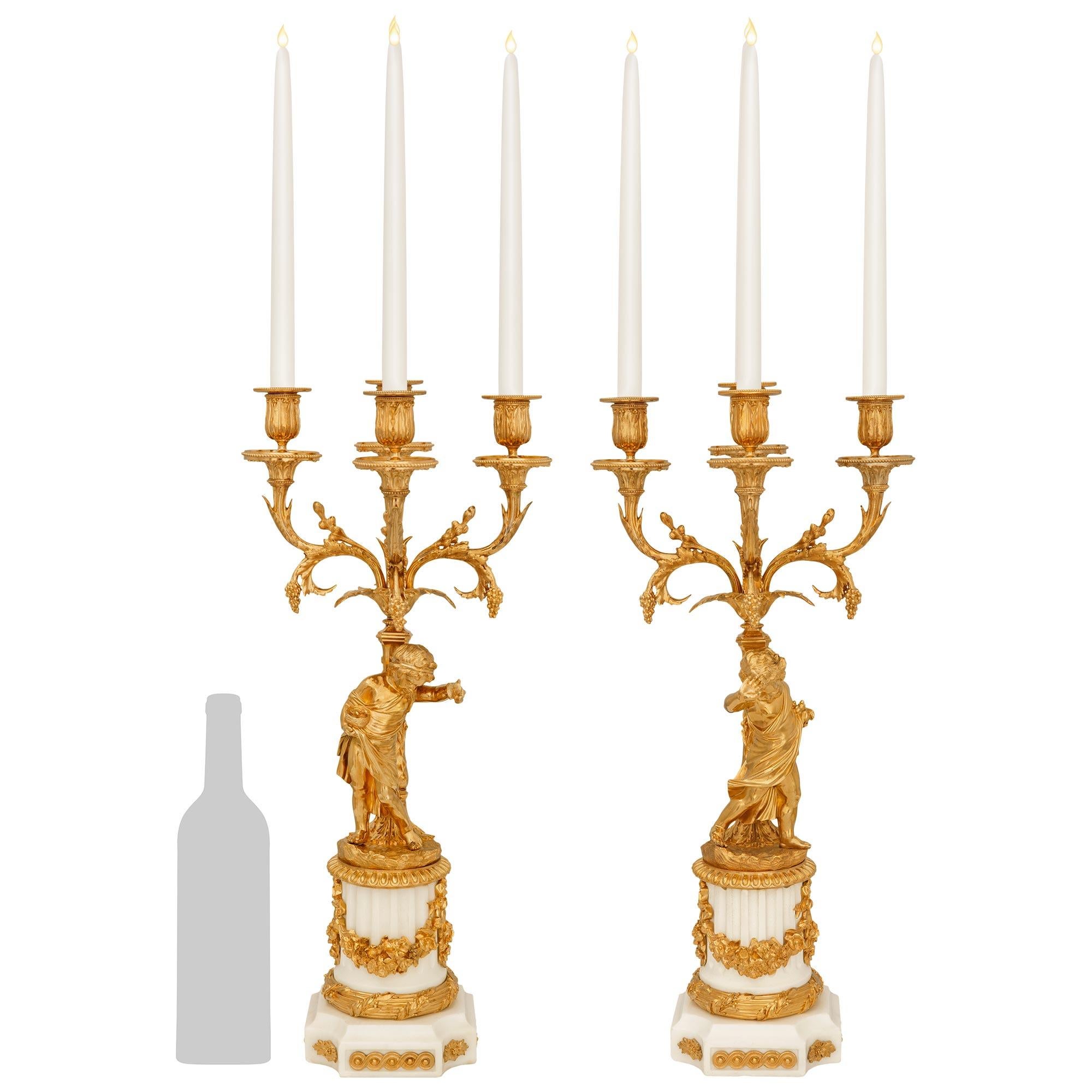 Una vera coppia di alta qualità di scarpe francesi del XIX secolo in stile Luigi XVI.  Candelabri in ormolu e marmo bianco di Carrara. Questa splendida coppia di candelabri a quattro bracci si erge su basi quadrate in marmo con angoli concavi e