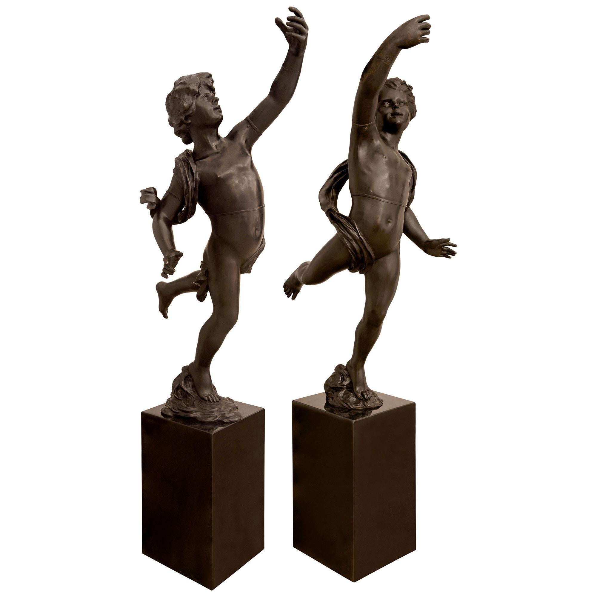 Ein beeindruckendes und sehr großes, echtes Paar französischer neoklassizistischer, patinierter Bronzestatuen tanzender Putten aus dem 19. Dieses sehr dekorative Statuenpaar steht auf quadratischen, rechteckigen Sockeln aus schwarzem Granit mit fein