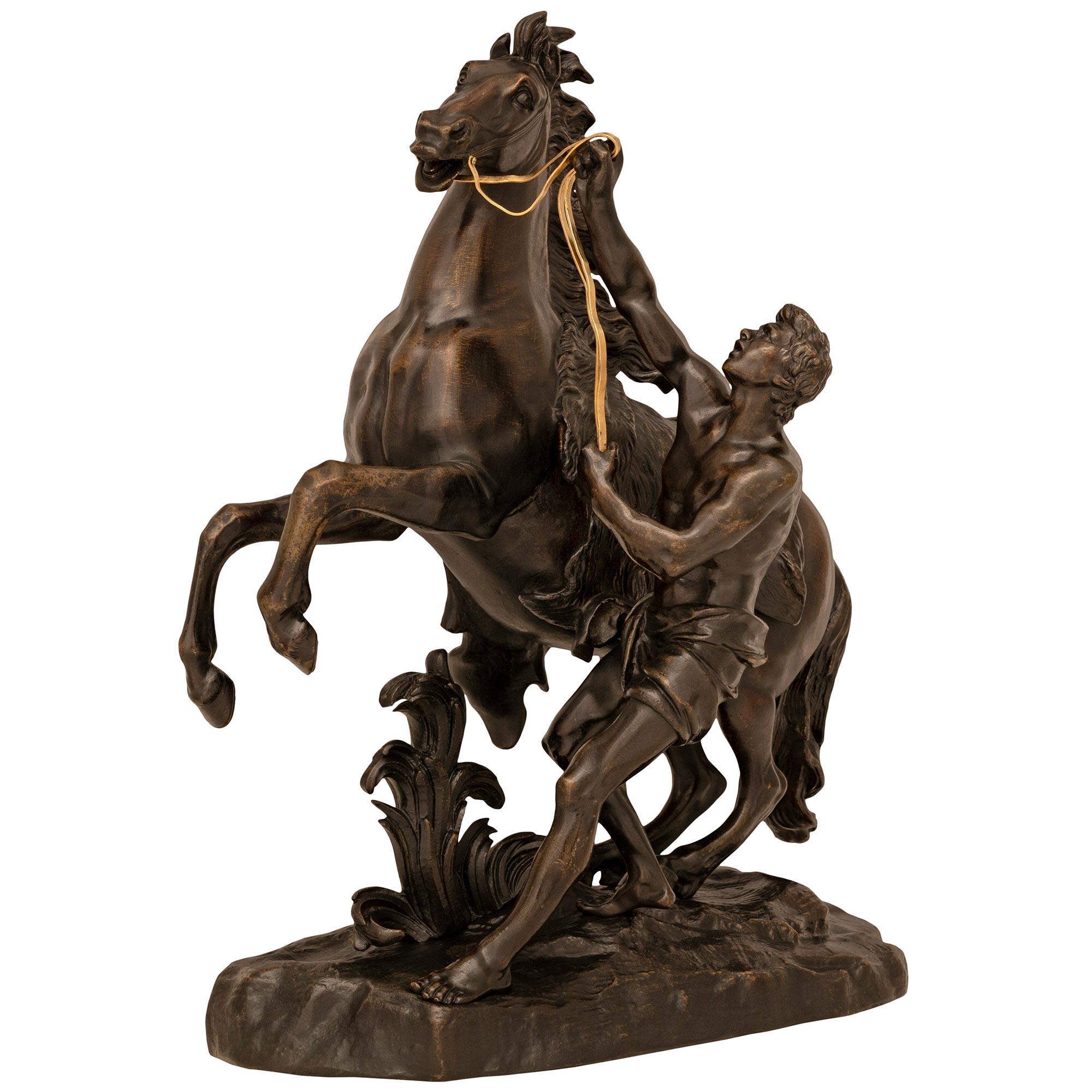 Une paire impressionnante et de grande taille de statues de chevaux Marli en bronze patiné du XIXe siècle, d'après un modèle de Coustou. Chaque statue est érigée sur une base conçue comme un rocher et un sol où les étalons merveilleusement détaillés