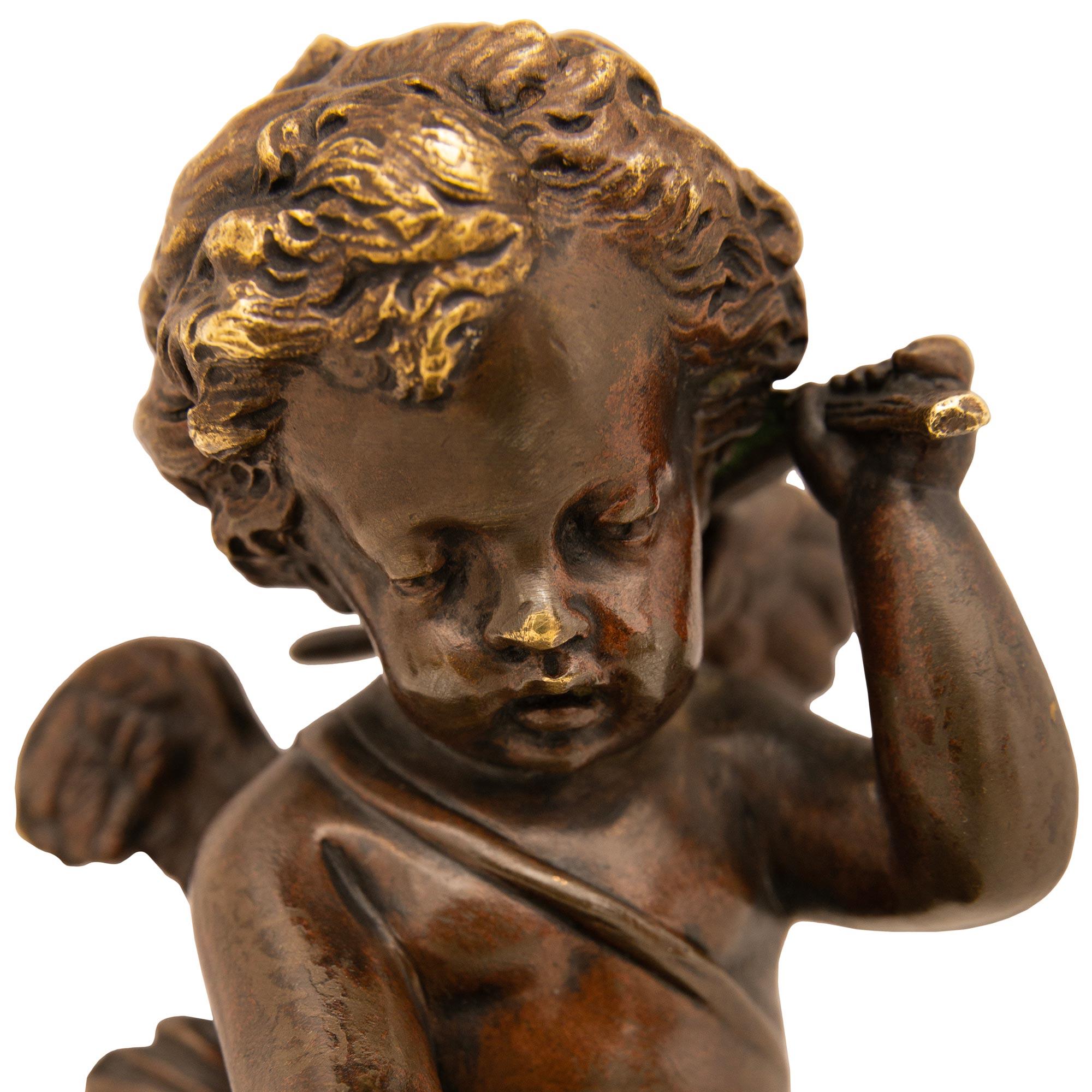 A lovely true pair of French 19th century Rouge Griotte marble and patinated Bronze cherub statues. Each charming statue is raised on a circular Rouge Griotte marble base supporting the winged cherubs above. One of the winged cherubs is gently